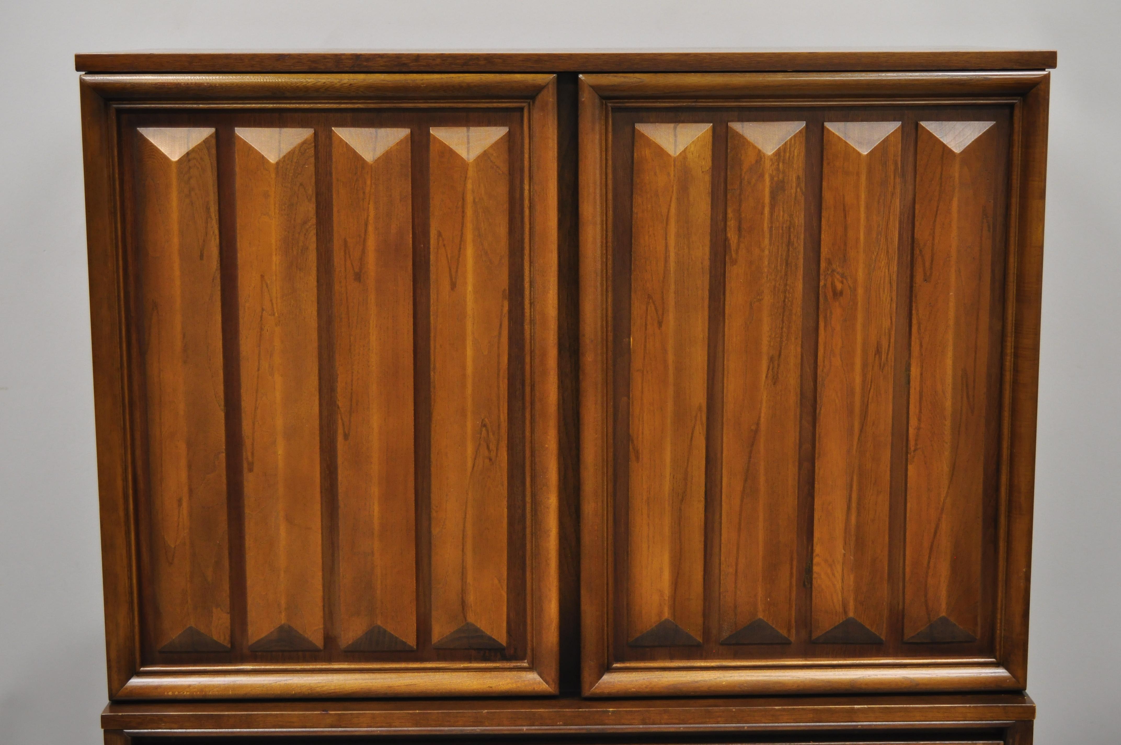 Mid-Century Modern sculpted walnut V-leg tall chest dresser cabinet. Item features tapered 