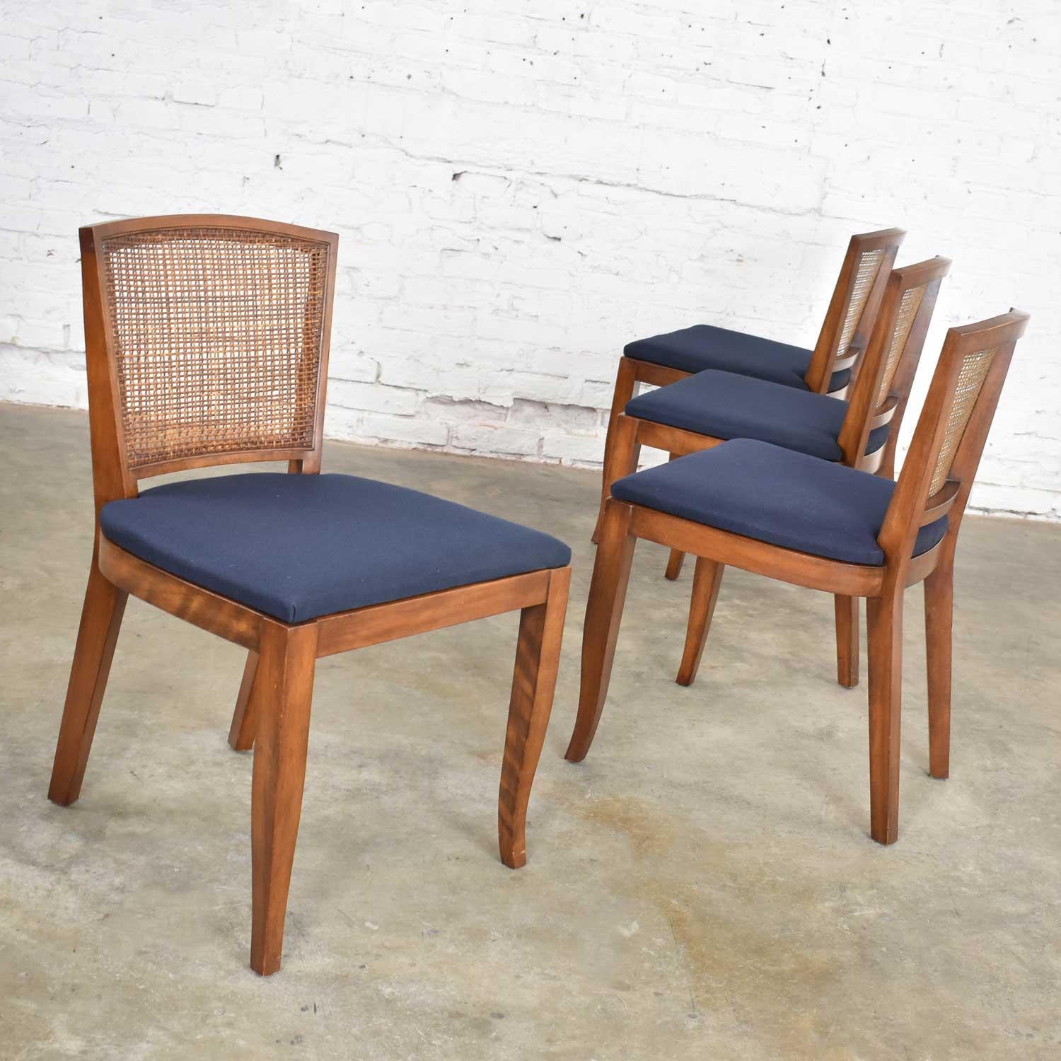 Handsome set of 4 Mid-Century Modern dining chairs with cane backs and newly upholstered seats. They are in wonderful vintage condition. One chair has a small repair to the caning, but you must search to find it. The seats have a new black/dark navy