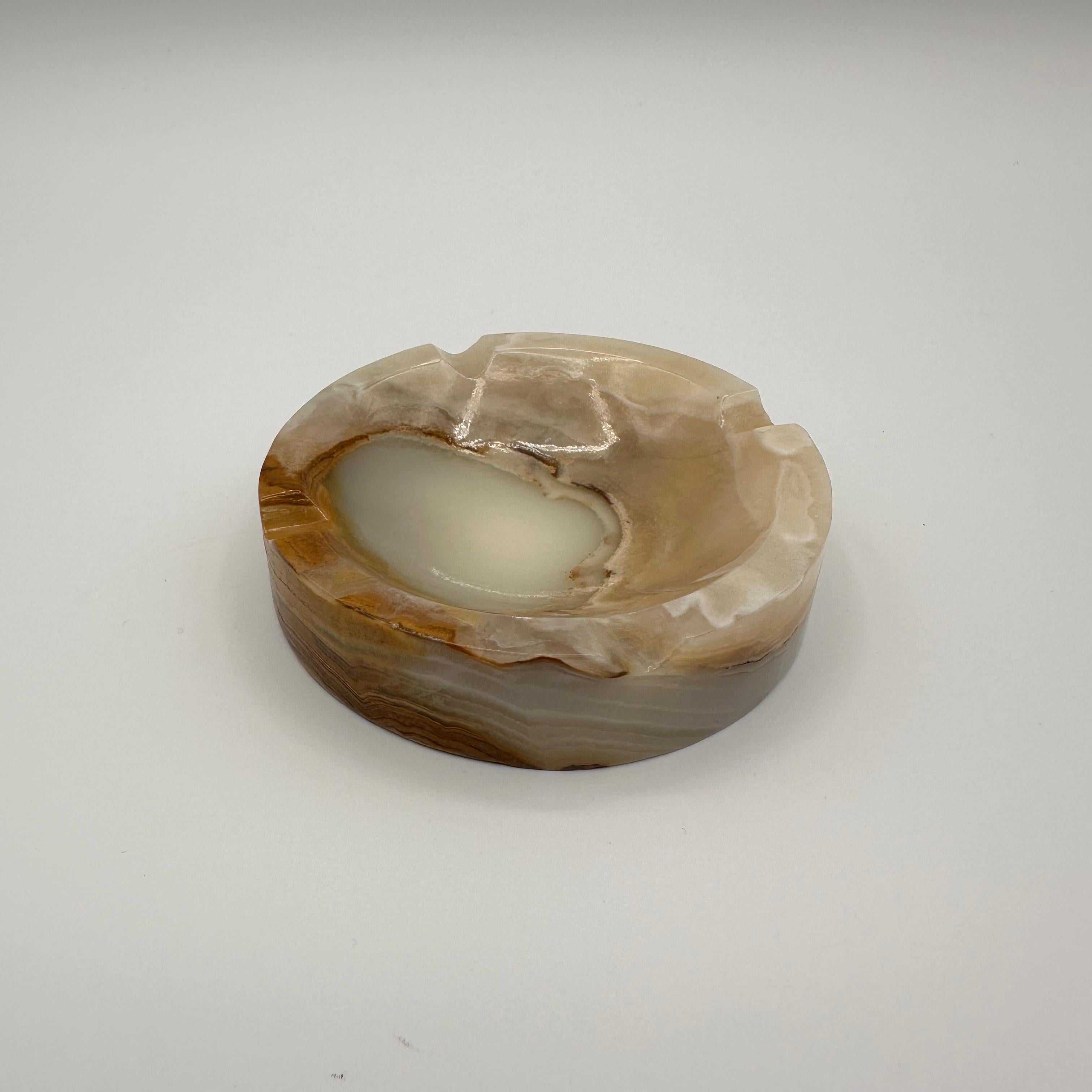 Vintage mid century modern small round ashtray made from a beautifully layered and striated piece of onyx stone in shades of brown, tan and beige. An amazing piece of stone that shows the natural process of the sediment banding and forming over