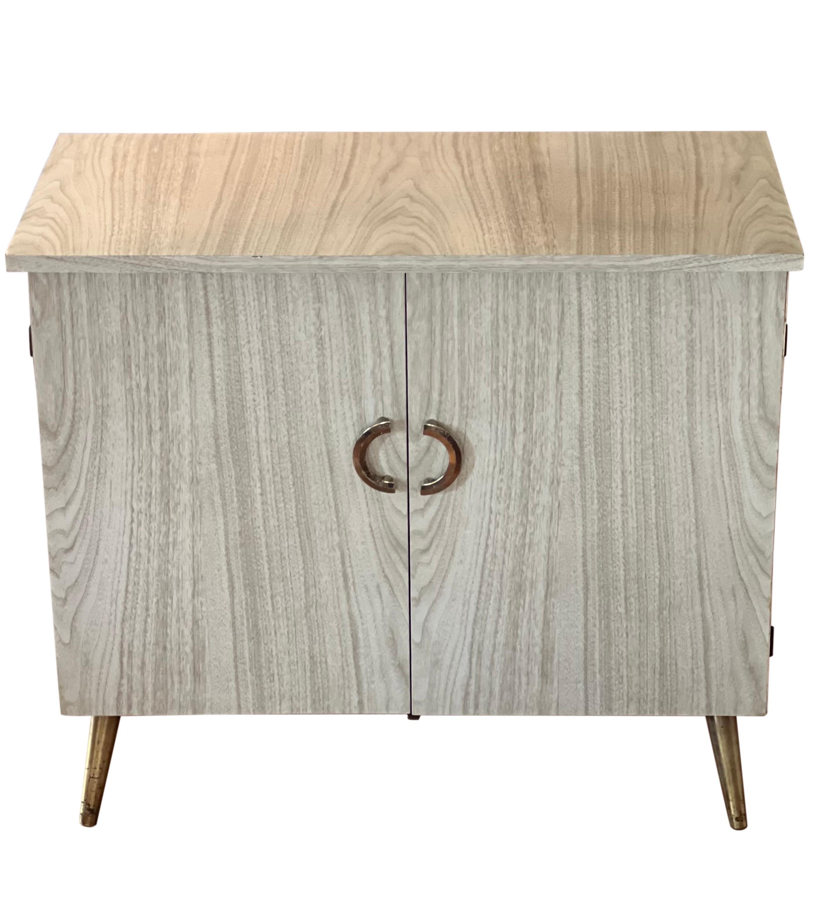 Wonderful vintage mid century modern laminated small sideboard or cabinet.  

This versatile cabinet is a practical  size and may be useful in any room.  With classic mid century modern design, it features two cabinet doors with brass half moon