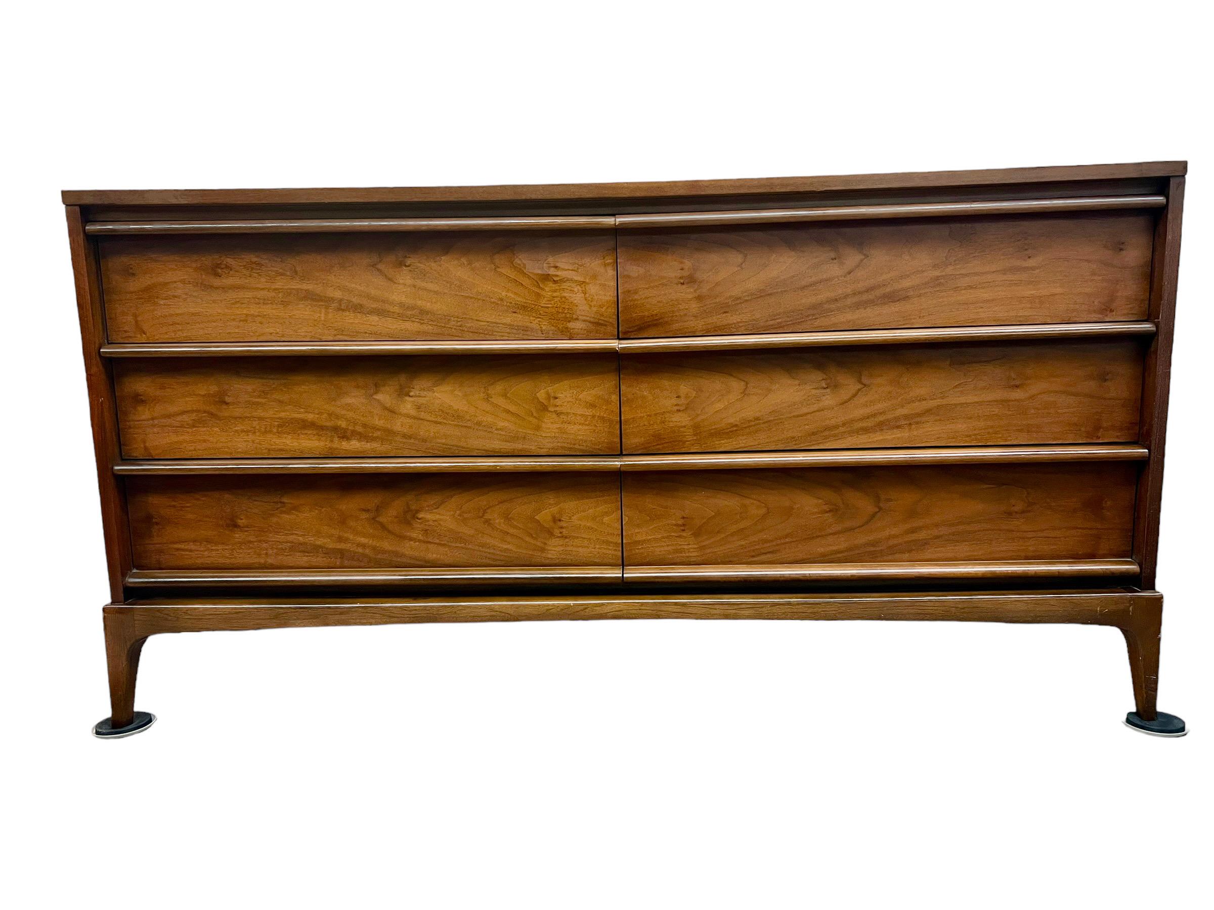 This Vintage Mid Century Modern Walnut Dresser was Manufactured by Lane. It is 6 Drawer Lowboy Style with a Generous Amount of Storage Space. The Wood Grain Detail on the Drawer Front is Impressive. This Piece has a Solid Wood Top and Carved Wood