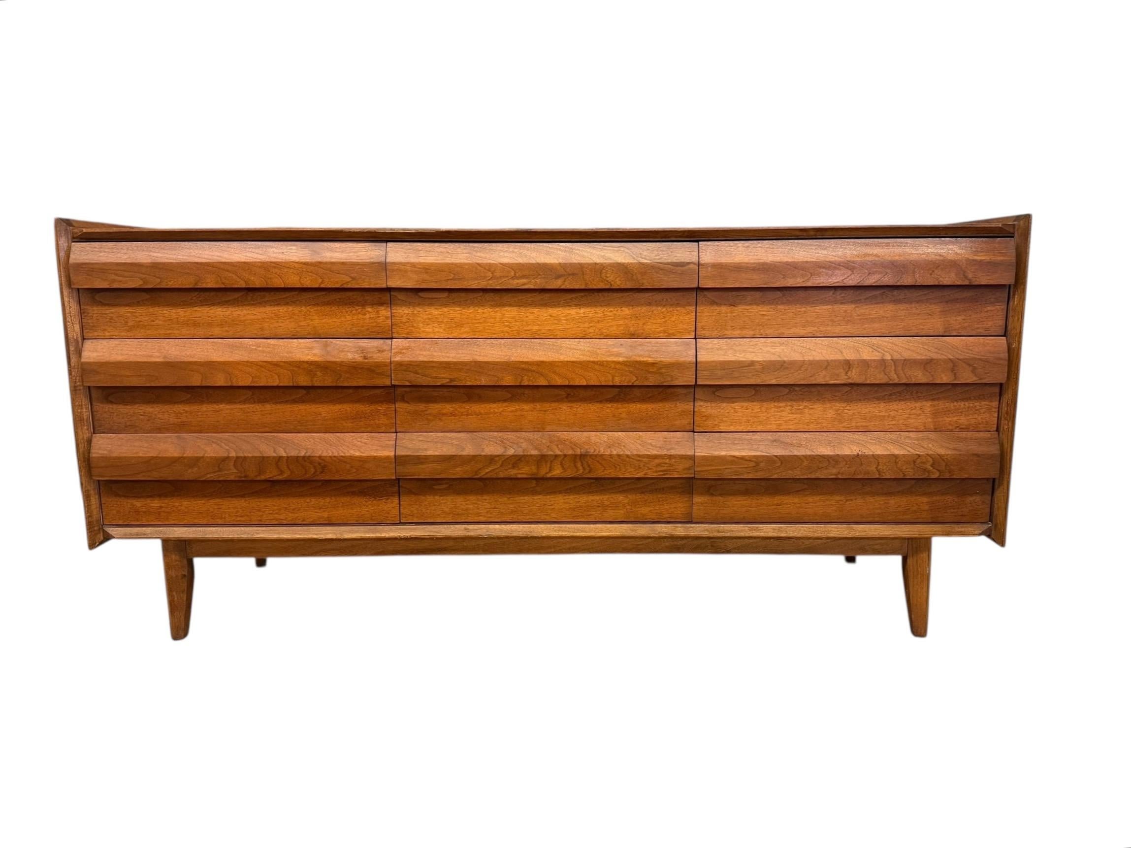 Une élégante commode à 9 tiroirs en noyer de la marque Lane First Edition, datant des années 1960. Il s'agit d'un magnifique exemple de l'artisanat du milieu du siècle de Lane Furniture. Comprend neuf tiroirs à lamelles. Une pièce extrêmement bien