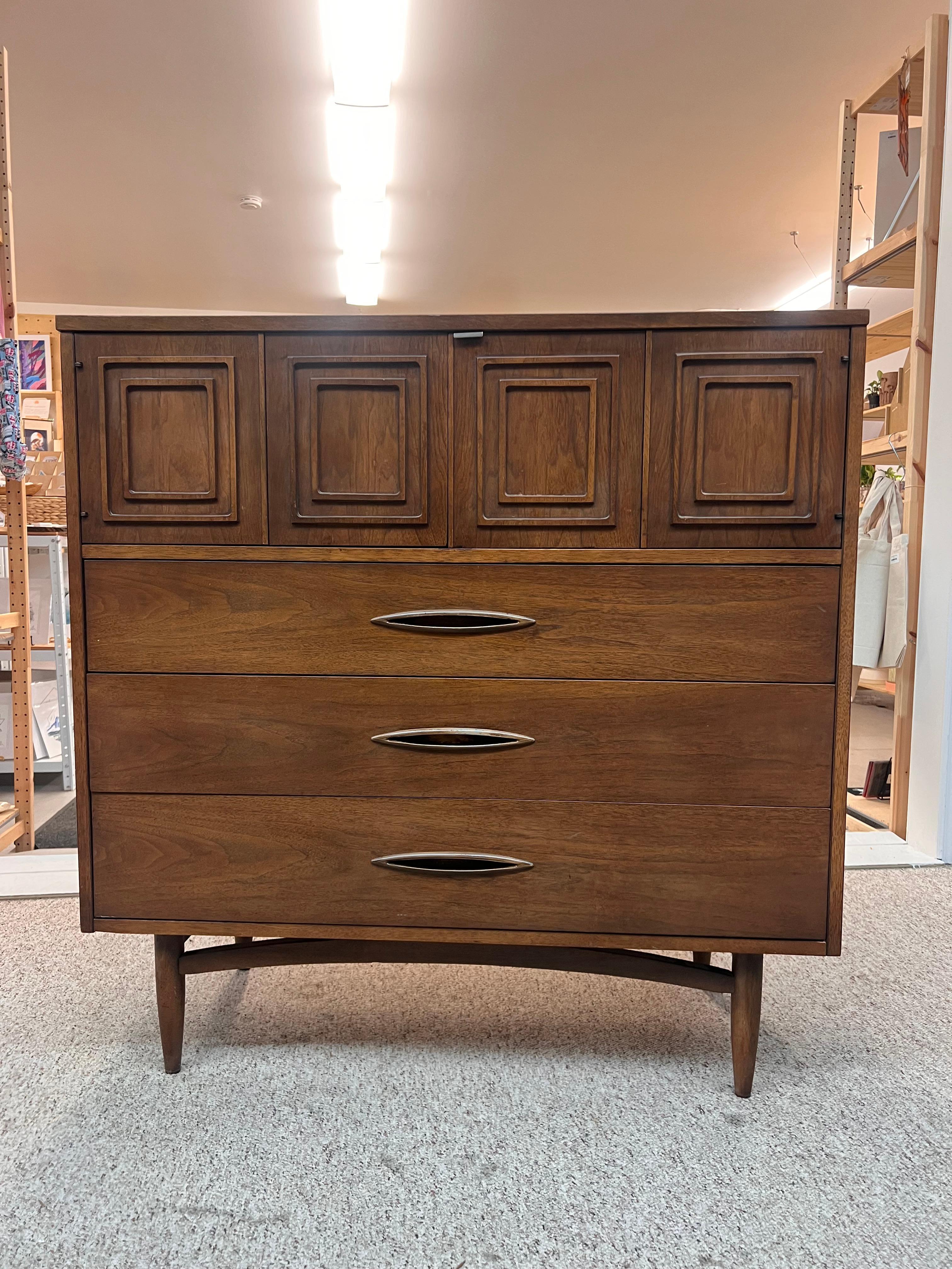 Élégante commode en noyer avec des compartiments divisés derrière deux portes à charnières et trois tiroirs spacieux en dessous. Broyhill Premier de la collection Sculpture. Quelques petites imperfections dues à l'âge et à l'utilisation, mais dans