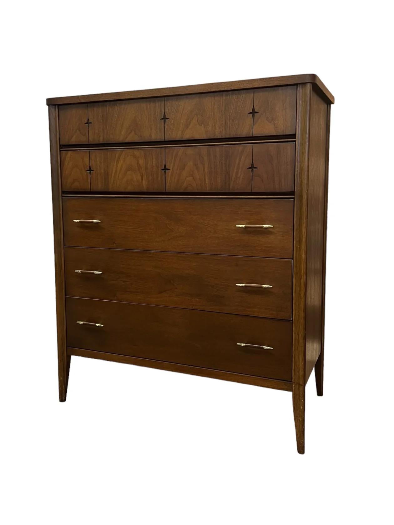 Die Broyhill Saga Kommode aus der Mitte des Jahrhunderts strahlt mit ihrem schlichten, minimalistischen Design zeitlose Eleganz aus. Sie zeichnet sich durch klare Linien und ein reichhaltiges Walnuss-Finish aus, das die natürliche Maserung des