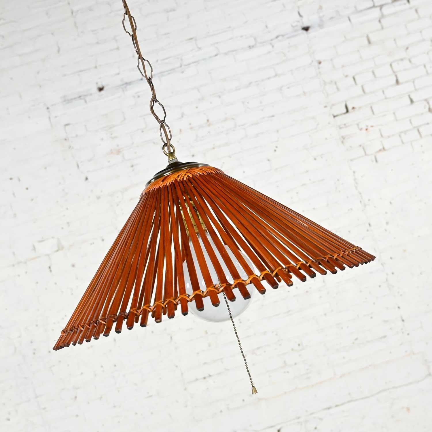 Handsome vintage Mid-Century Modern split rattan hanging conical light with large round bulb (which we will include), antiqued brass cap or finial and chain. Beautiful condition, keeping in mind that this is vintage and not new so will have signs of
