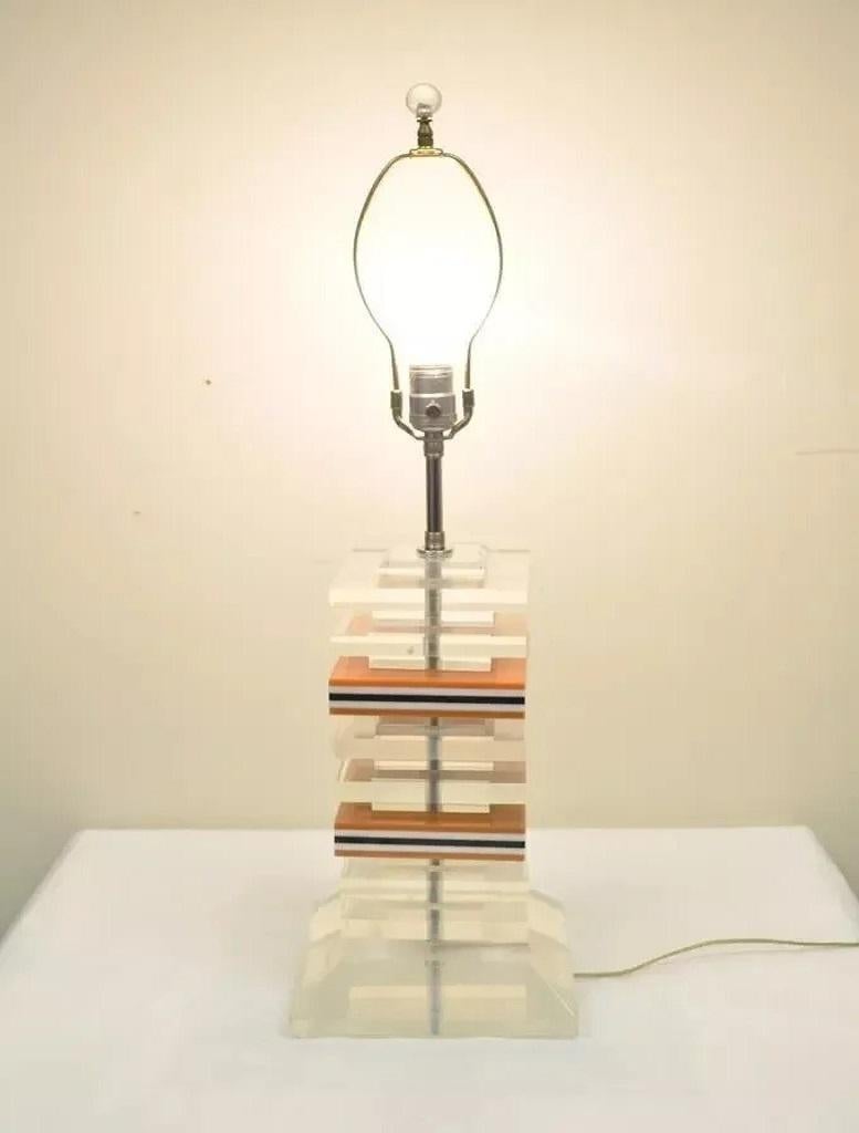 Vintage Mid Century Modern Stacked Lucite Acrylic Skyscraper Table Lamp. Item features stacked lucite center alternating with clear, pale, orange, white, and black layers, beautiful mid century design. Designer is unconfirmed but very similar to the