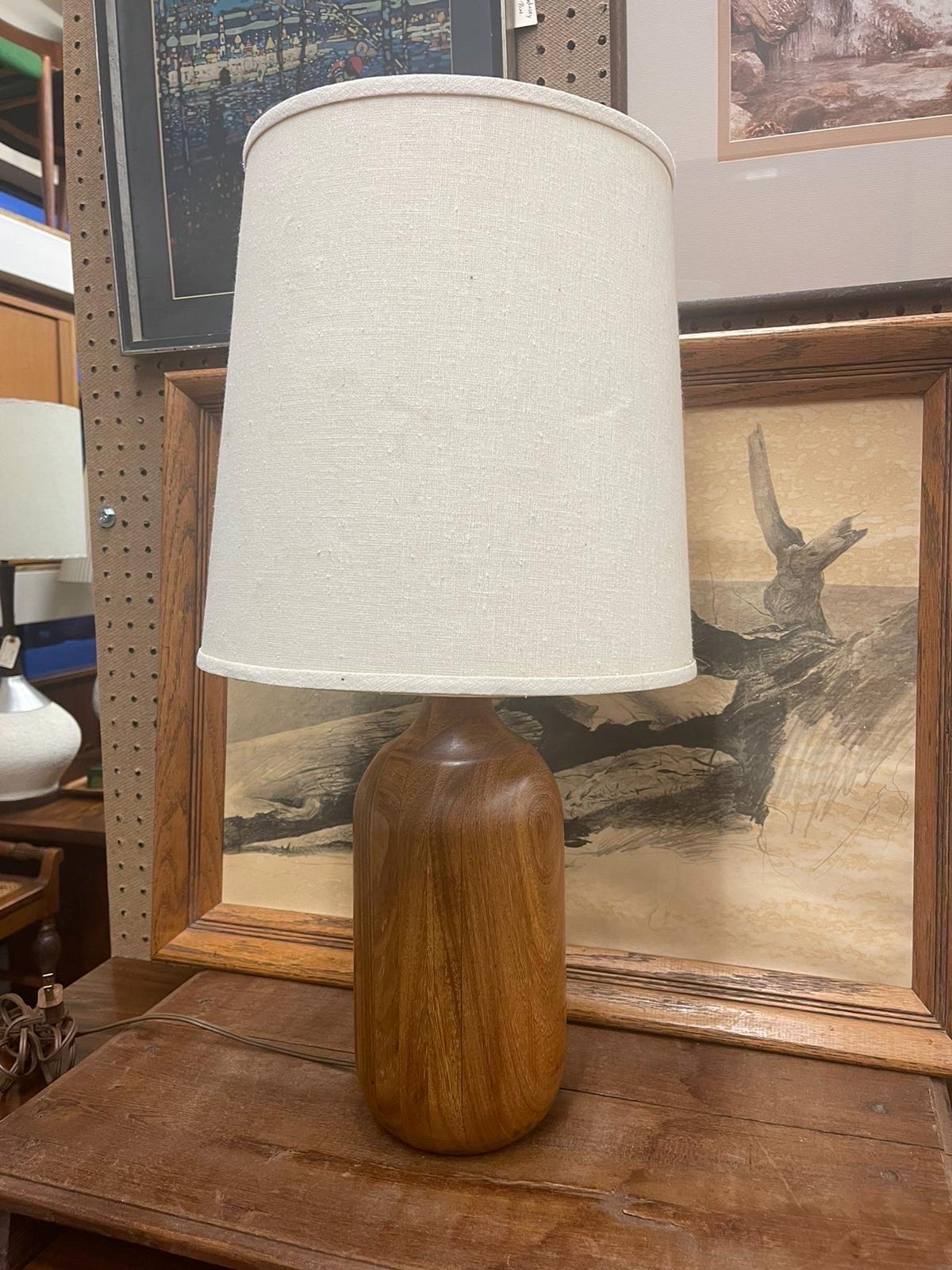 Vintage Table Lamp with WalnutToned Base. Circa 1960s/1970s. Oatmeal Tone Lamp Shade Included. Light Bulb not Included. Possibly Teak. Vintage Condition Consistent with Age as Pictured.

Dimensions. Base 6 Diameter; 24 H
                  Shade. 12