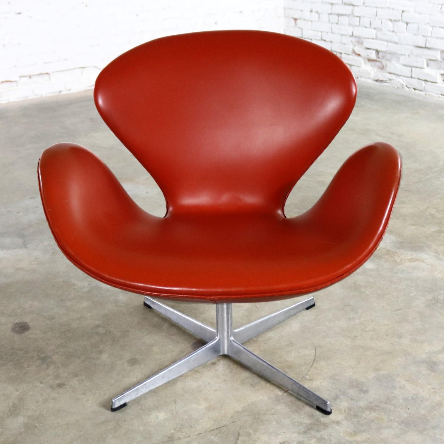 Iconic Mid-Century Modern Swan chair by Arne Jacobsen for Fritz Hansen in cognac colored Naugahyde vinyl upholstery. It is in wonderful vintage condition with normal wear and tear for age and use. There are a few nicks to the vinyl that have been