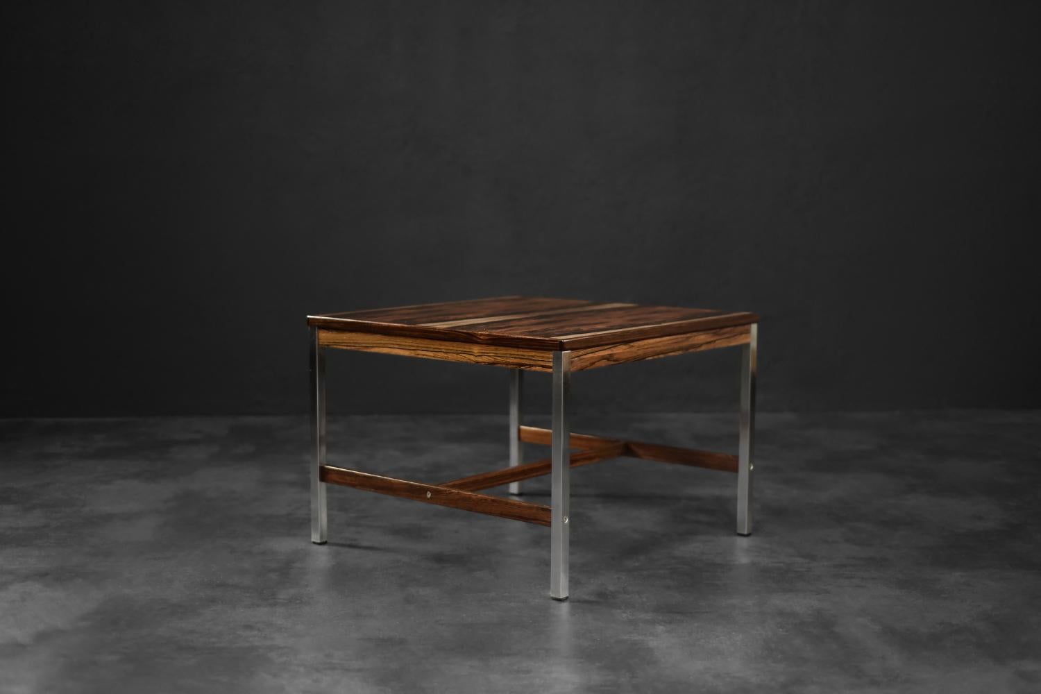 Questo tavolino è stato realizzato dal produttore svedese HMB Möbler, a Rörvik, negli anni Sessanta. Il piano quadrato è rifinito in palissandro con un colore scuro ed espressivo e una venatura forte e dura. Le ricche venature creano un effetto