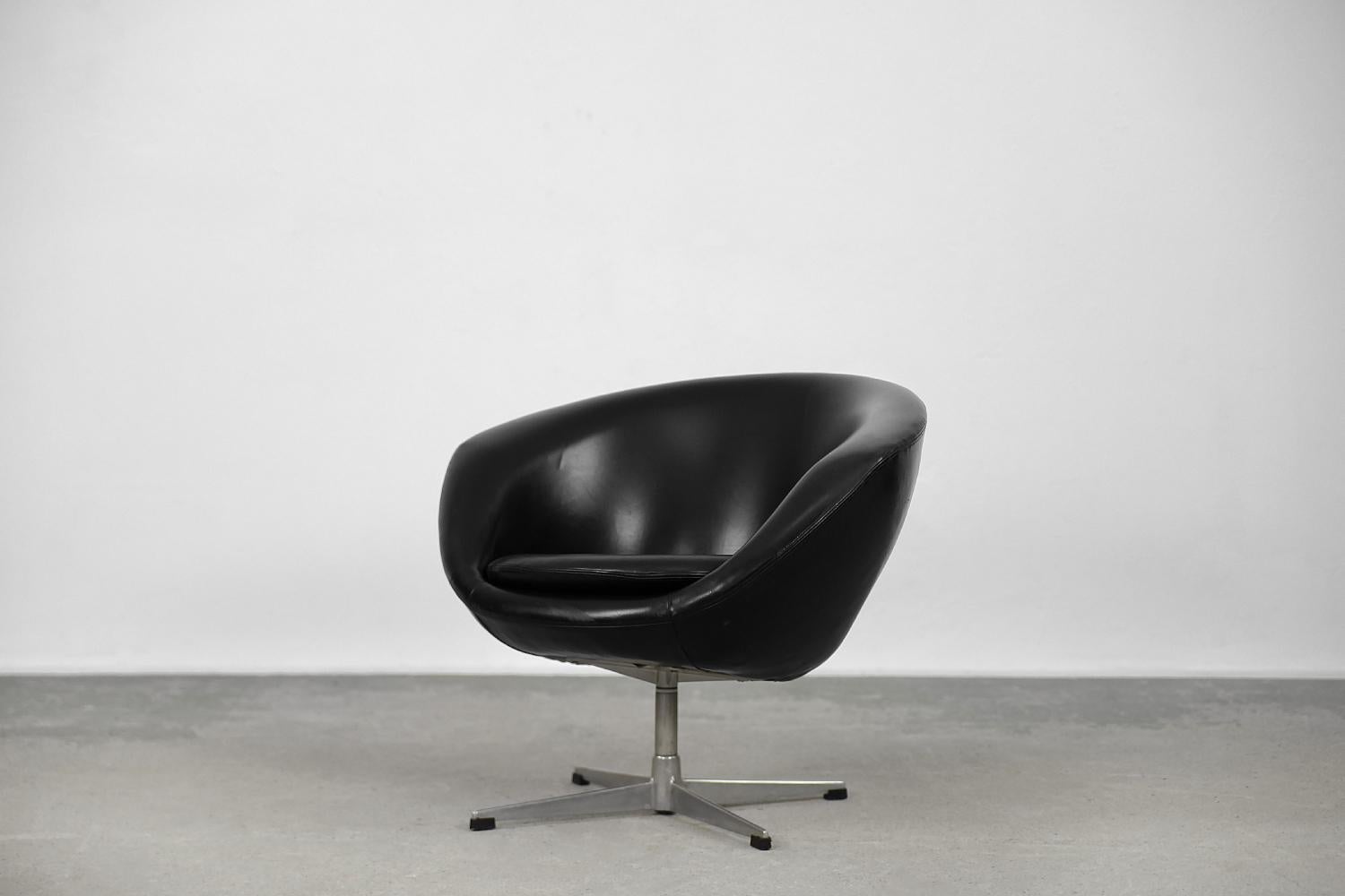 This Rondo swivel armchair was manufactured by the Swedish S.M. Wincrantz Möbelindustri AB, Skövde during the 1960s. The armchair has a bucket-shaped form and is upholstered with black vinyl. TIt has a metal swivel leg. The deep seat has a loose