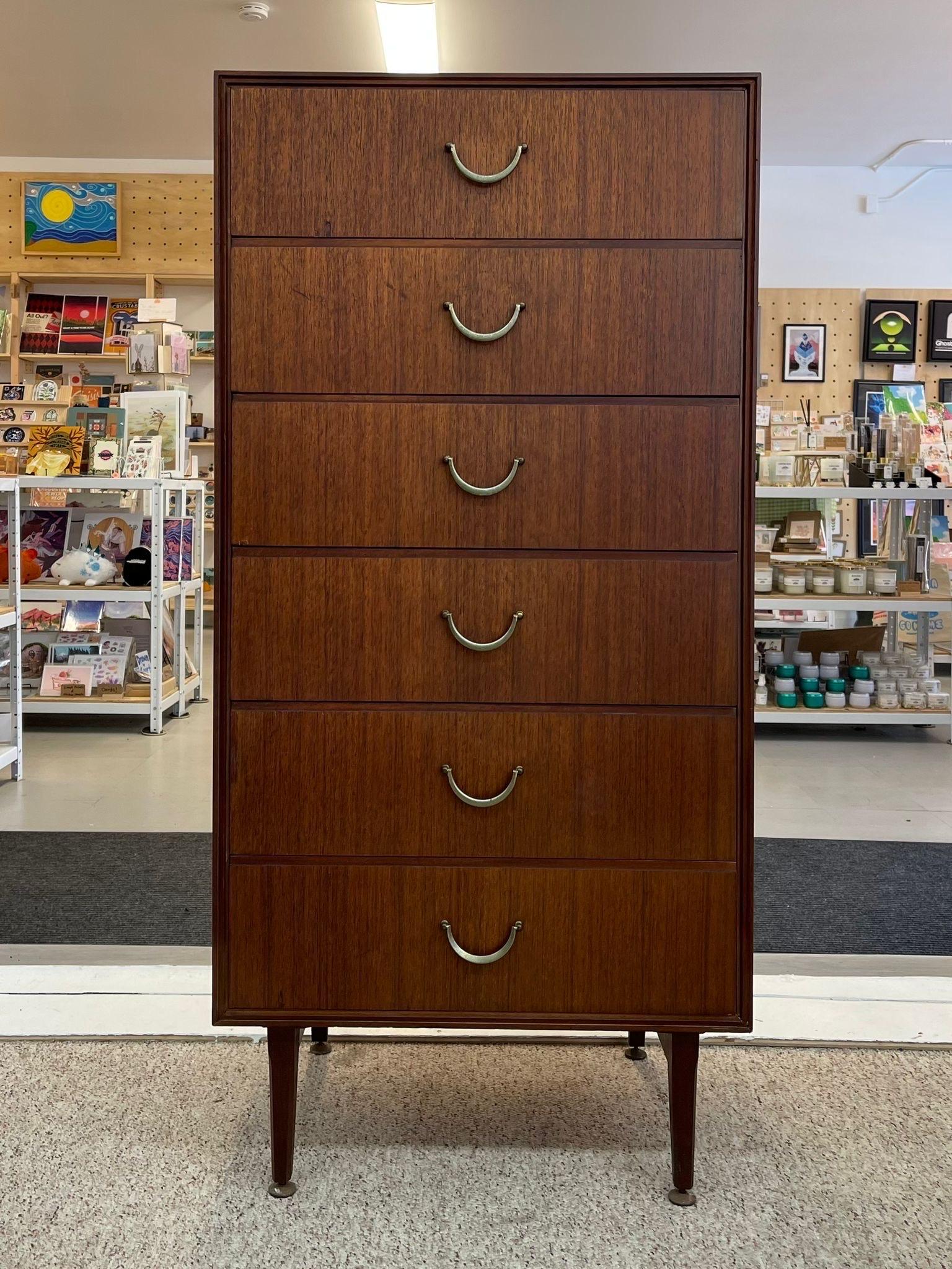 Walnut Toned piece with 6 dovetailed drawers and original brass toned handles. Tapered Legs. Makers mark in the back of the top drawer. Vintage Condition Consistent with Age as Pictured. Circa 1960s.

Dimensions. 24 W ; 18 D ; 50 H
