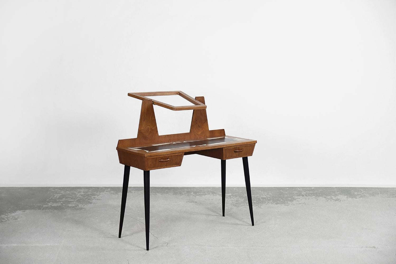 The modernist dressing table with a mirror was made in Scandinavia during the 1960s. It is finished with teak wood in a warm shade of brown. It has two drawers. A mirror is in a geometric frame, the angle of which can be freely adjusted. The