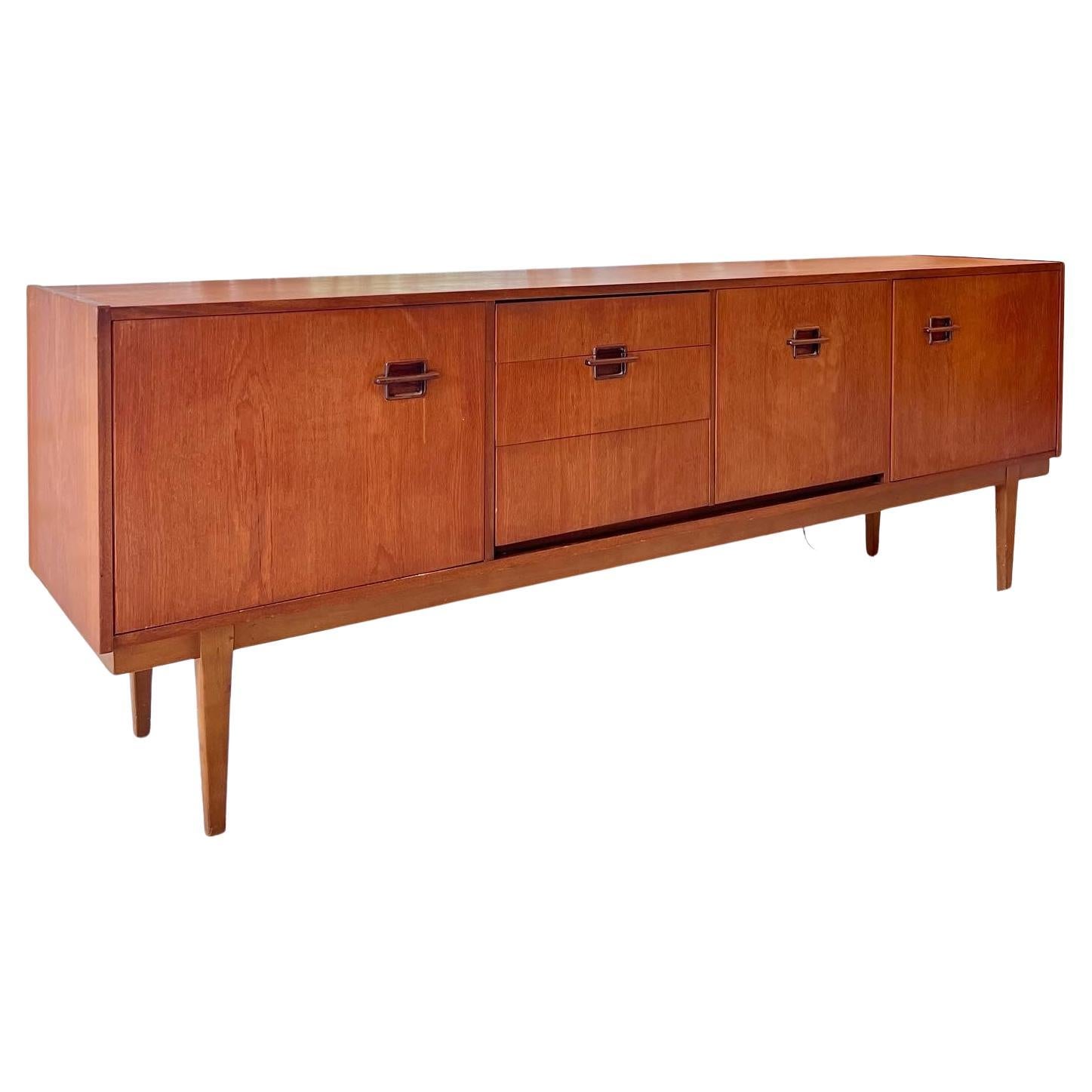 This long and stylish teak sideboard by Nathan furniture offers a wonderful array of storage spaces, including a unique front-drop cabinet. Wonderful handle design complements the classic vintage finish, perfect for any room in the home or office.