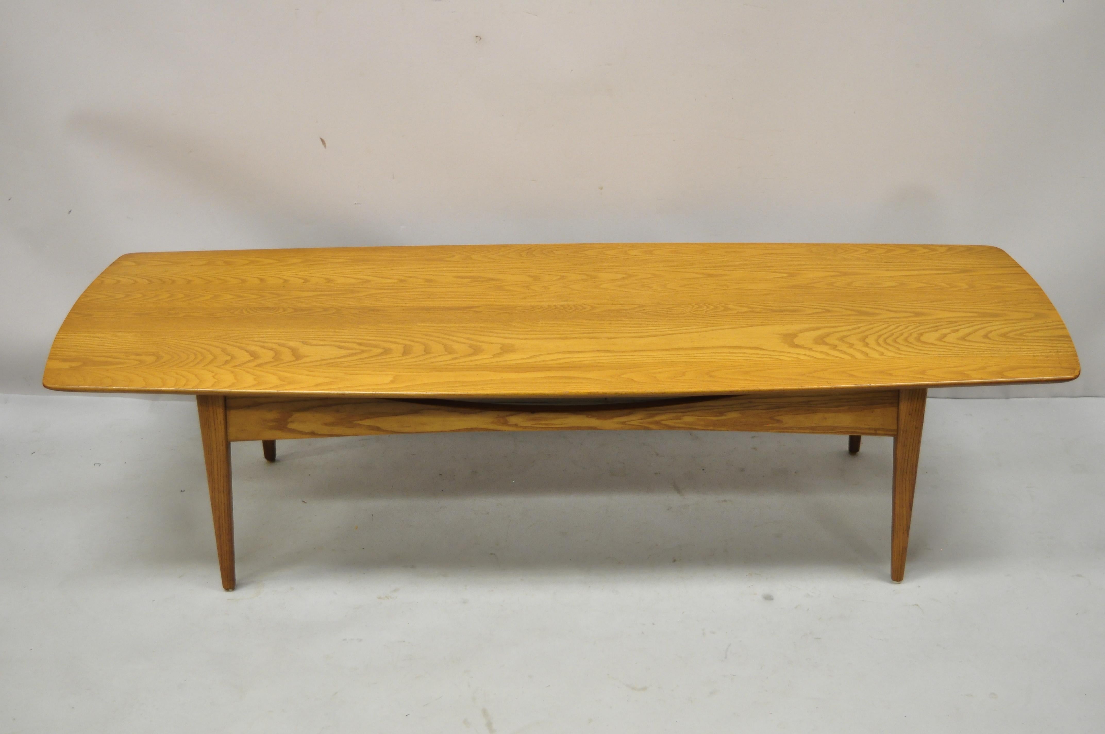 Vintage Mid-Century Modern teak wood long surfboard coffee table. Marked 701-G. Item features beautiful wood grain, tapered legs, clean modernist lines, quality American craftsmanship, great style and form, Circa mid 20th century. Measurements:
