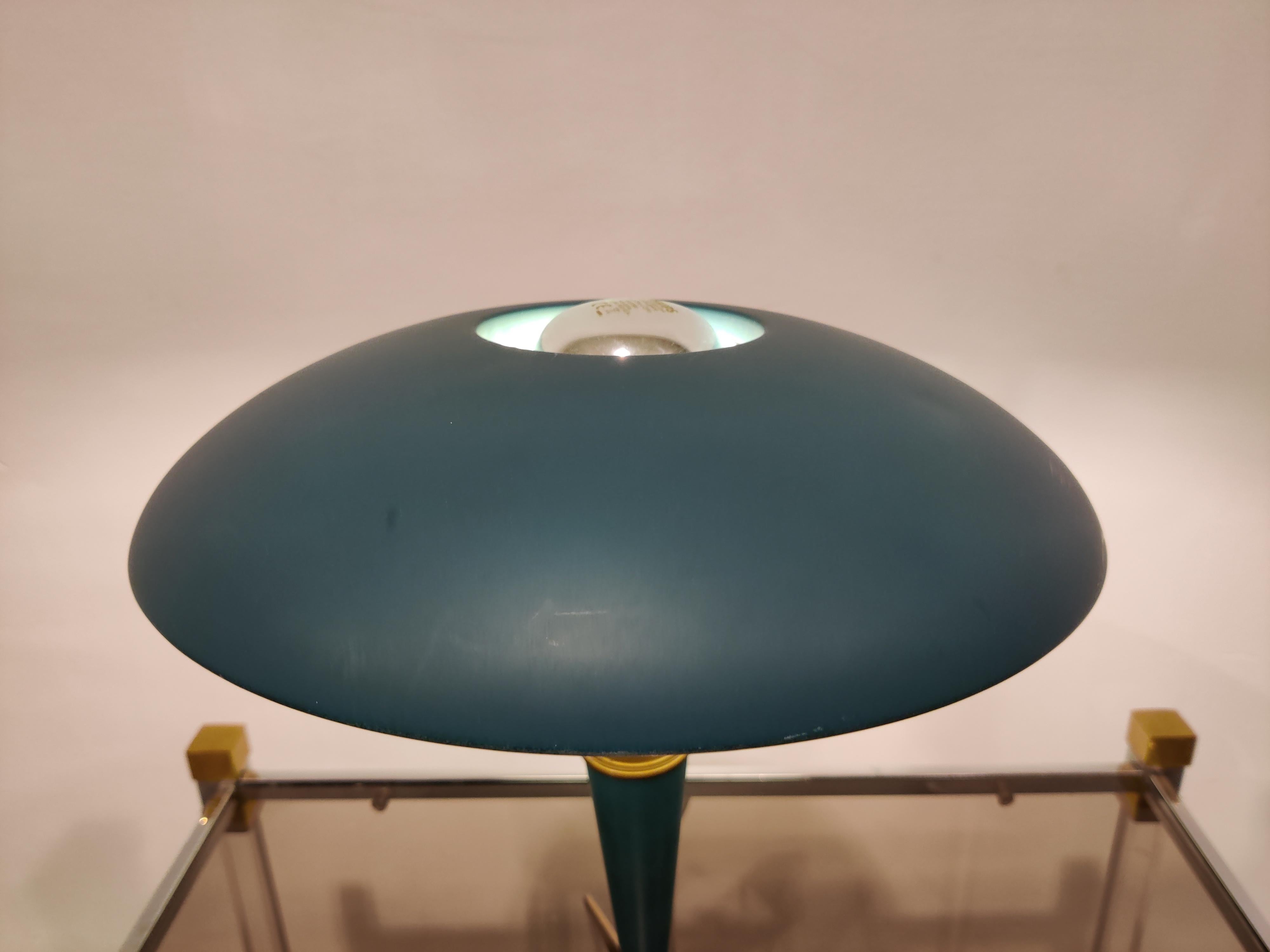 This midcentury table lamp model 'bijou' by Louis Kalff was introduced in the 1950s but it still looks modern today. 

The lampshade and base are made from blue/green metal, light enamel inner layer of the lamp shade to emit a soft light.

The
