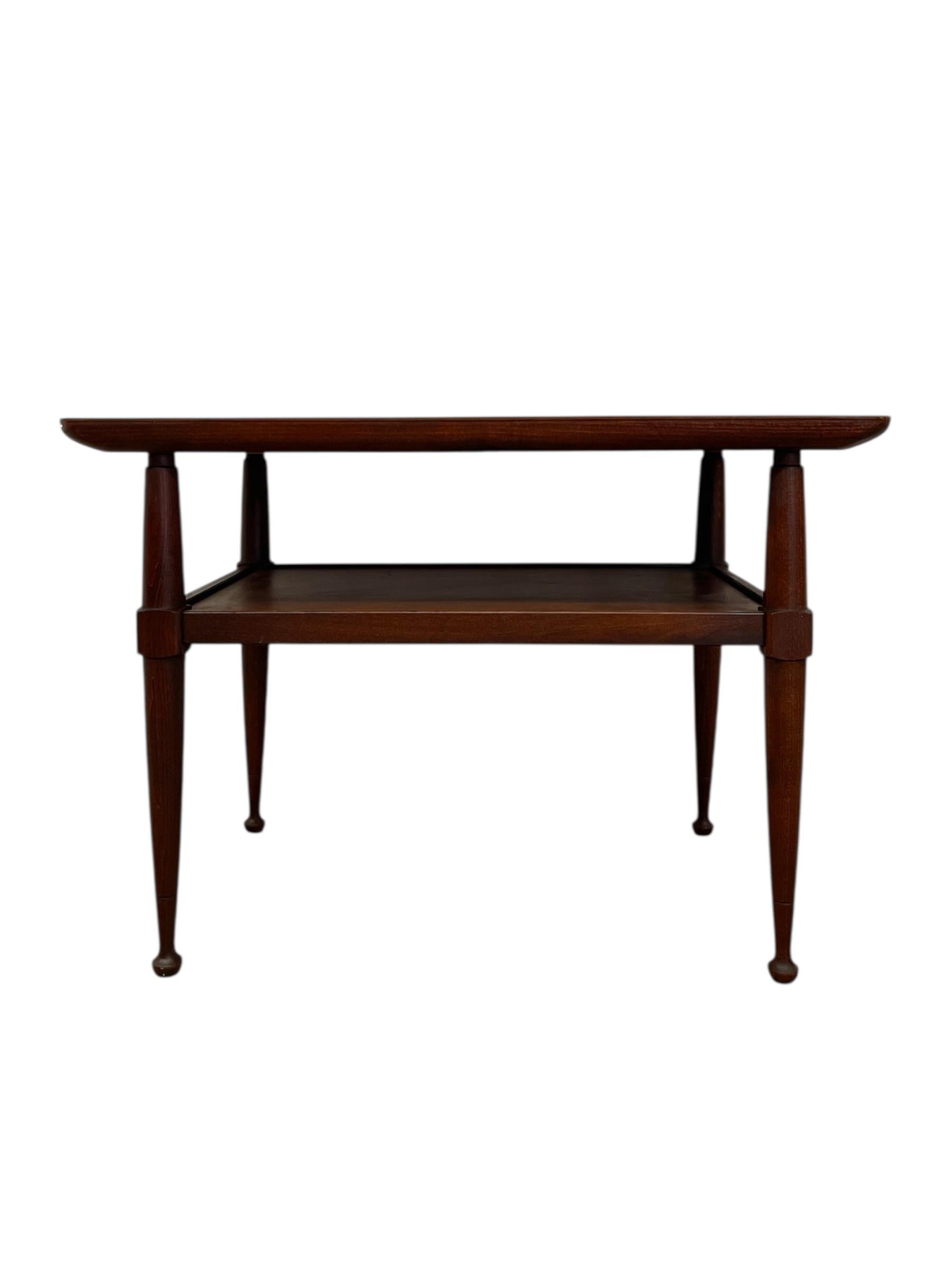 Una clásica mesa auxiliar moderna de mediados de siglo de elegantes proporciones y refinada artesanía. El diseño presenta una encimera rectangular con bordes suavemente redondeados, apoyada en cuatro patas cónicas que terminan en sutiles pies de