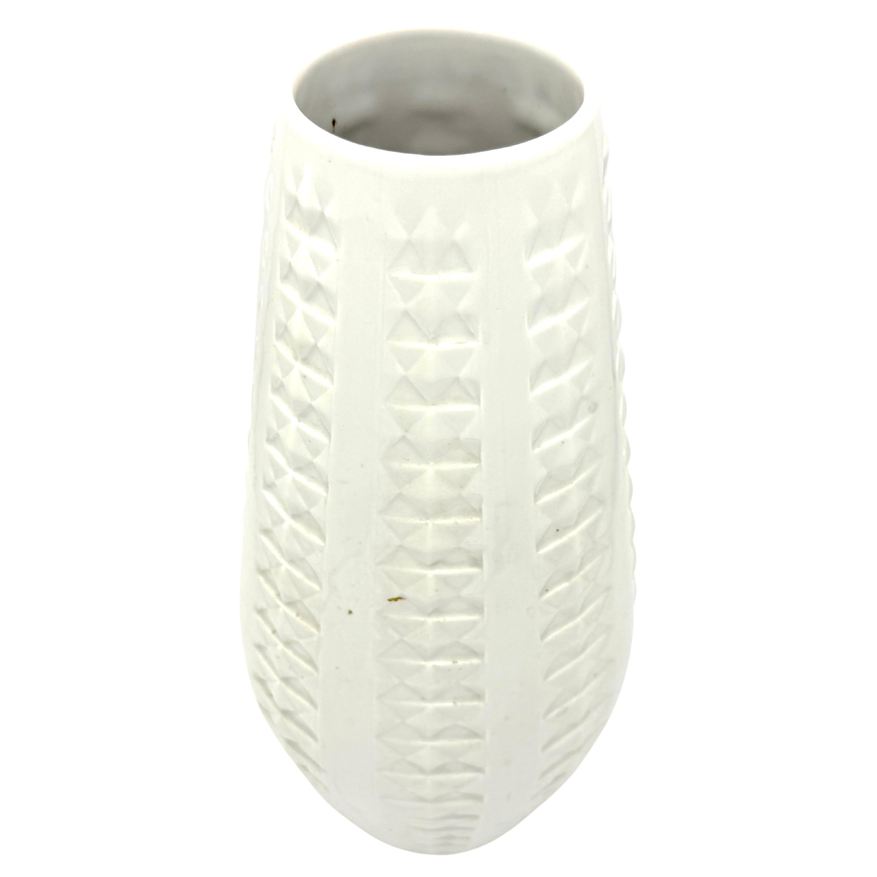 Ce grand vase a été mis en caisse par Arzberg.  au milieu du 20e siècle en porcelaine blanche. Le vase est décoré de motifs géométriques imprimés à l'intérieur de larges bandes verticales. Des ornements en forme de pyramide alternent avec des
