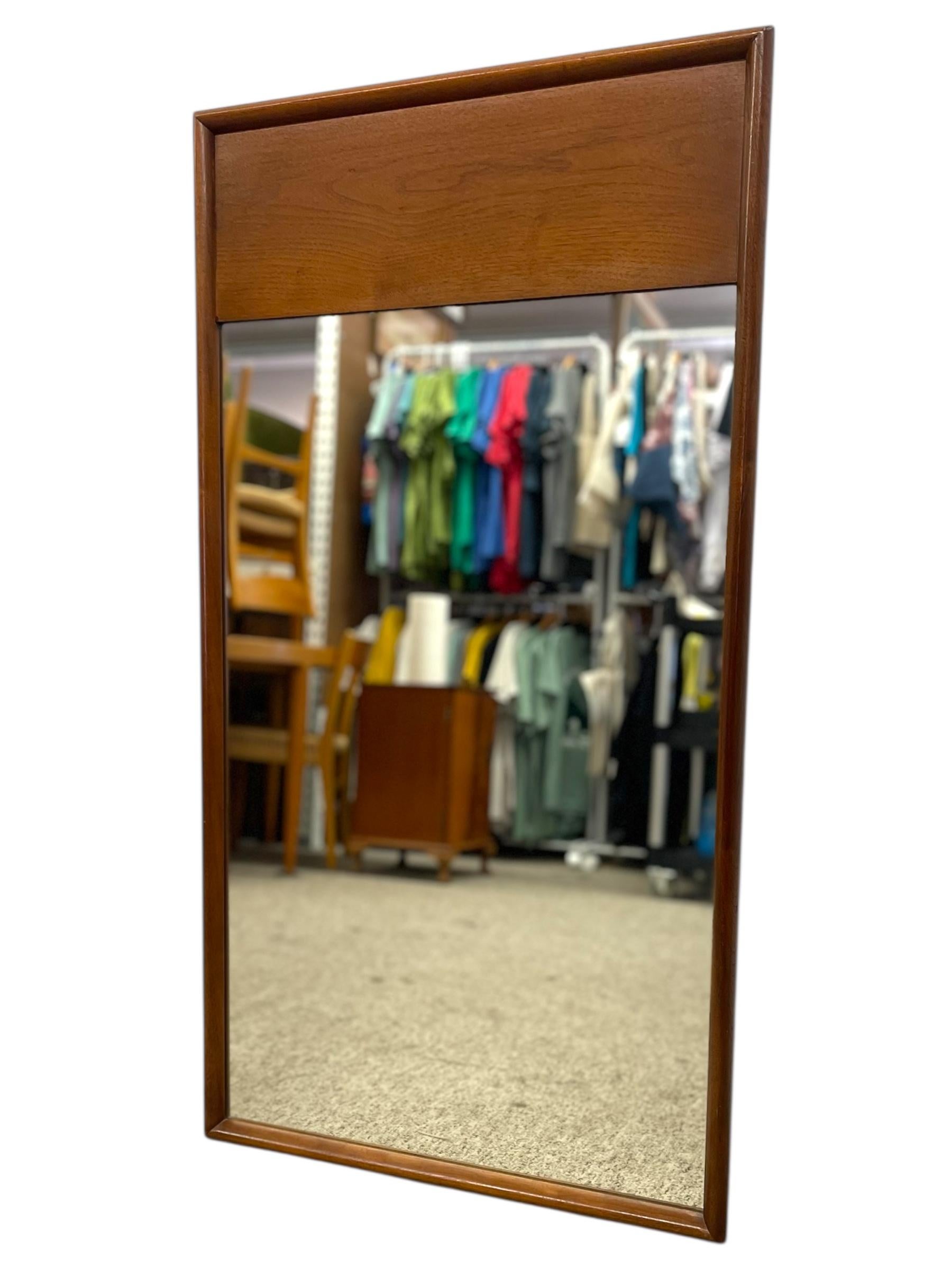  Miroir mural vintage du milieu du siècle, avec un cadre aux bords nets et sculptés et un panneau supérieur distinctif. Le ton chaud met en valeur le grain naturel du bois, ajoutant à la fois chaleur et raffinement à tout intérieur. Le design est