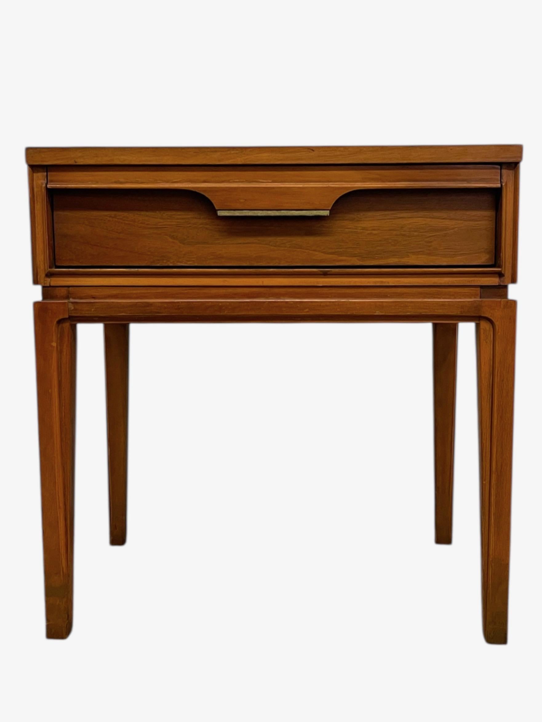 Una mesa auxiliar vintage de nogal moderno de mediados de siglo, de Basic Witz, Waynesboro, Virginia. Esta pieza presenta líneas modernistas limpias con patas cónicas y un solo cajón acentuado por un tirador esculpido empotrado. El cálido acabado en