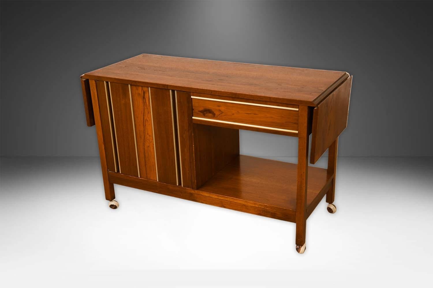 Absolutely beautiful and functional Mid-Century Modern Drop Leaf Bar Cart Console Table circa 1960s. This absolute jewel remains in nearly pristine condition.  This drop-leaf bar cabinet/ cart features richly grained walnut, with a fully finished