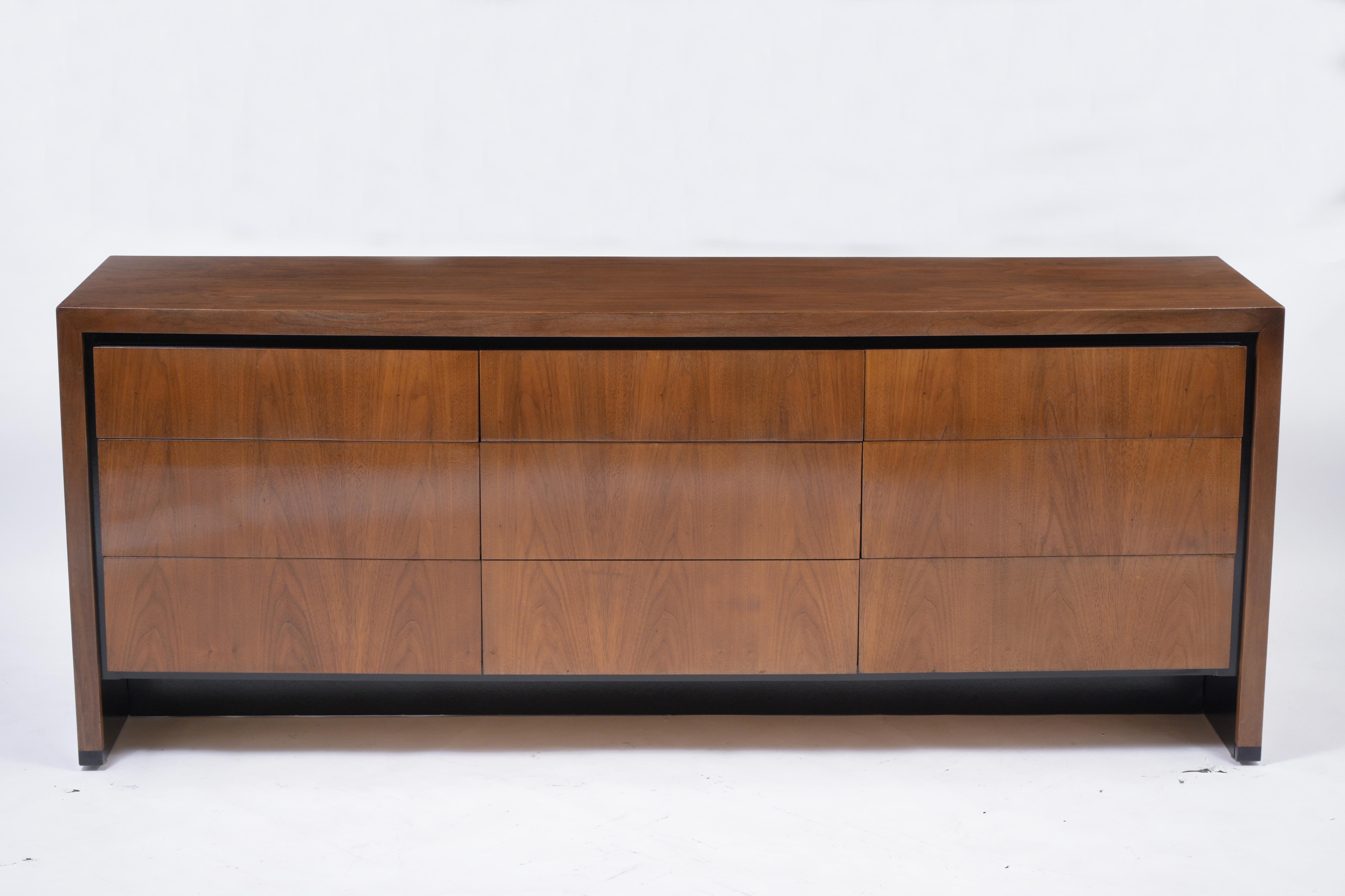 A modern 1960s chest of drawers handcrafted out of walnut wood features a dark walnut and ebonized color combination finished in a beautiful new lacquered finish. The dresser comes with nine pullout drawers with plenty of interior storage space that