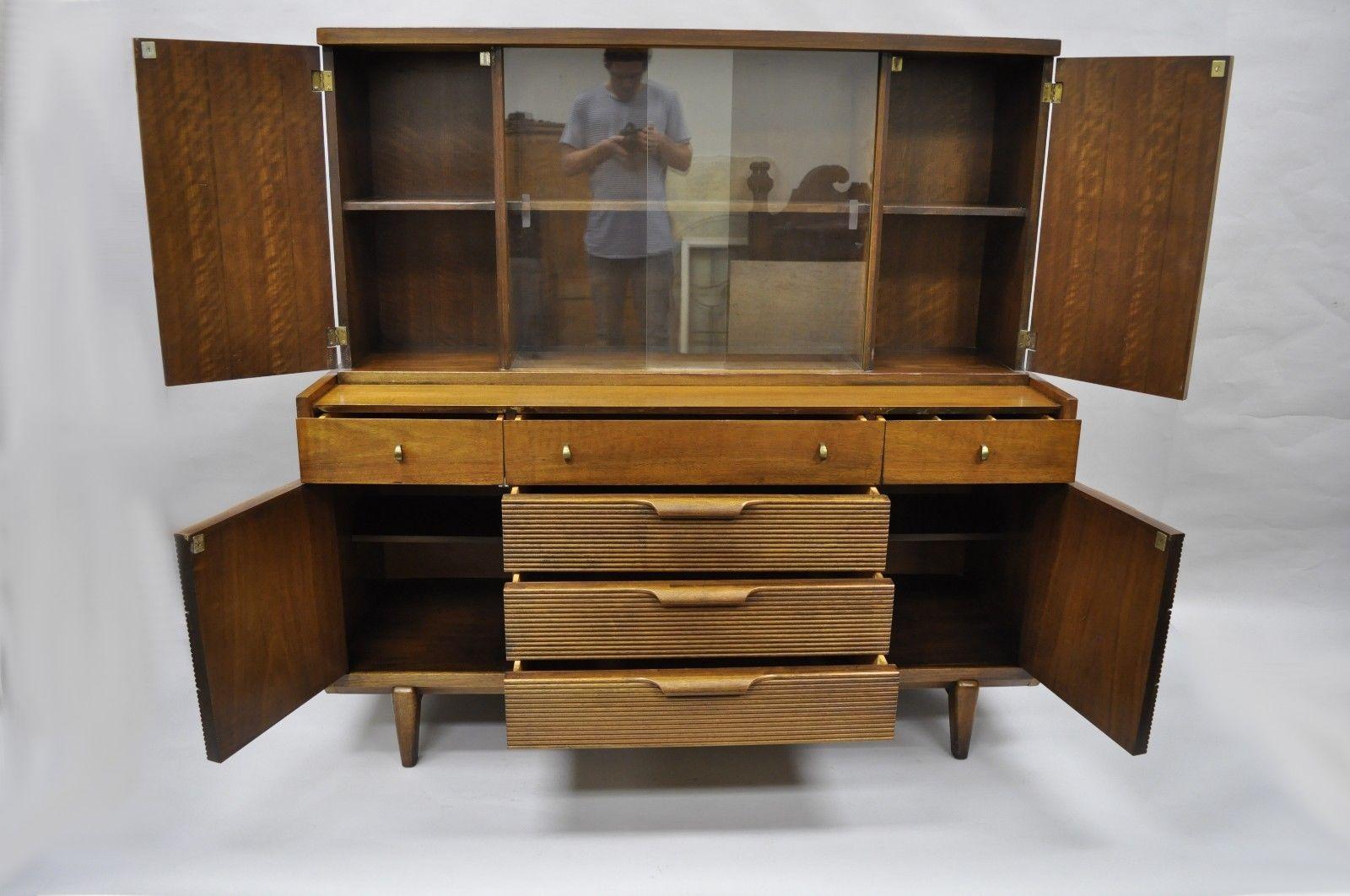 Vintage Mid-Century Modern walnut China cabinet hutch by Century. Item features two part construction beautiful wood grain, sculpted wood pulls, step out legs, two sliding glass doors, four swing doors, five drawers and unique brass pulls. Signed