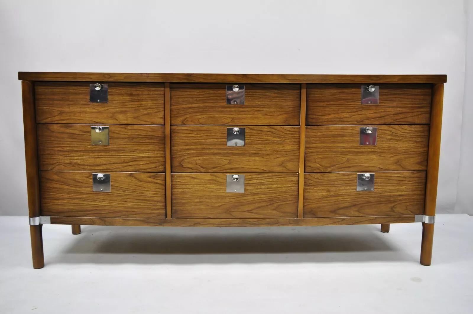 Cómoda Credenza Vintage Mid Century Modern de 9 cajones en nogal y cromo con espejo. El artículo incluye embellecedores y herrajes cromados, espejo a juego, hermosas vetas de madera, 9 cajones con cola de milano, gran estilo y forma, la madera tiene