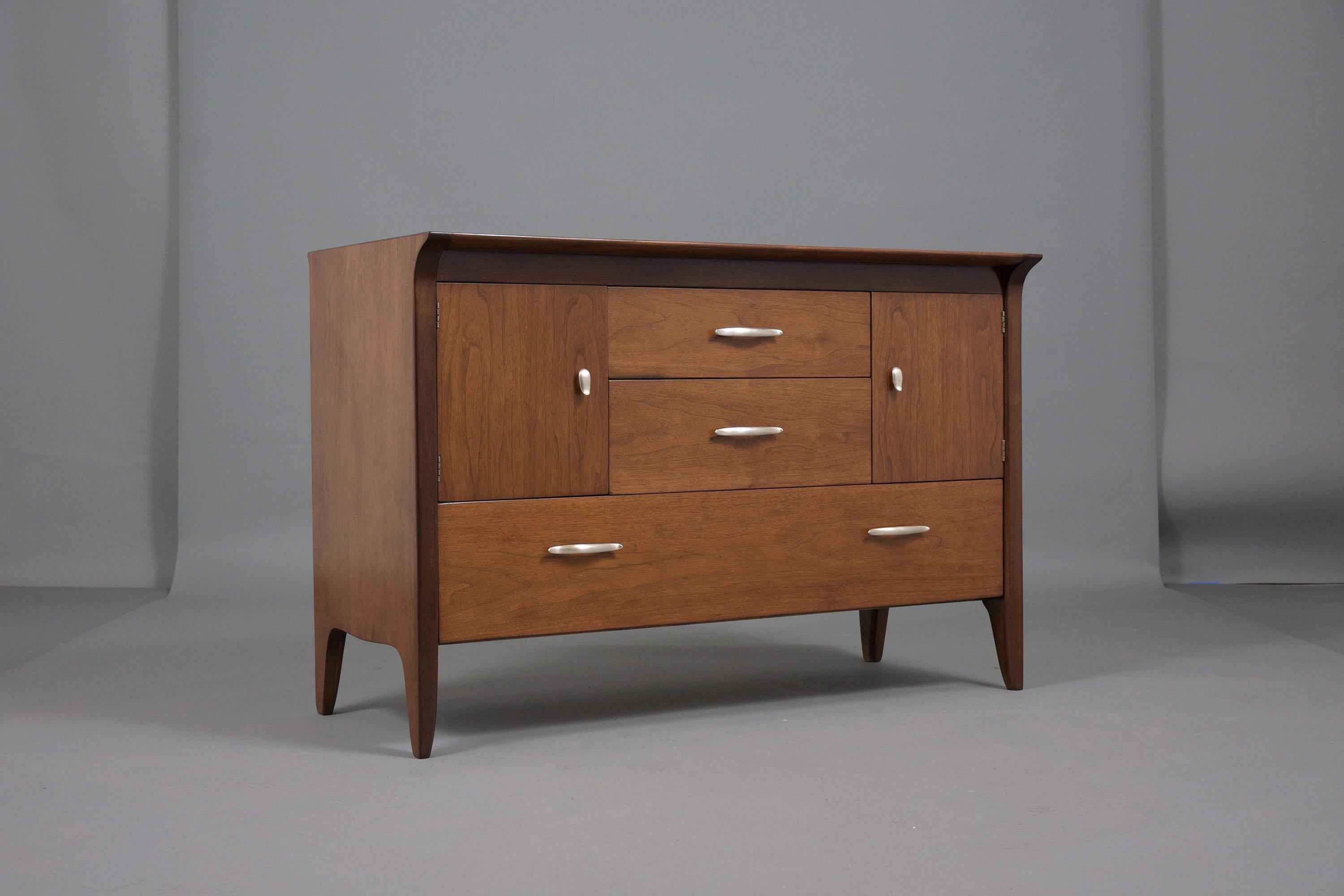 Experience the timeless elegance of our Mid-Century Modern Walnut Chest of Drawers, a masterpiece from the 1960s, expertly restored and refinished by our team of professional craftsmen. Crafted from high-quality walnut, this dresser has been stained