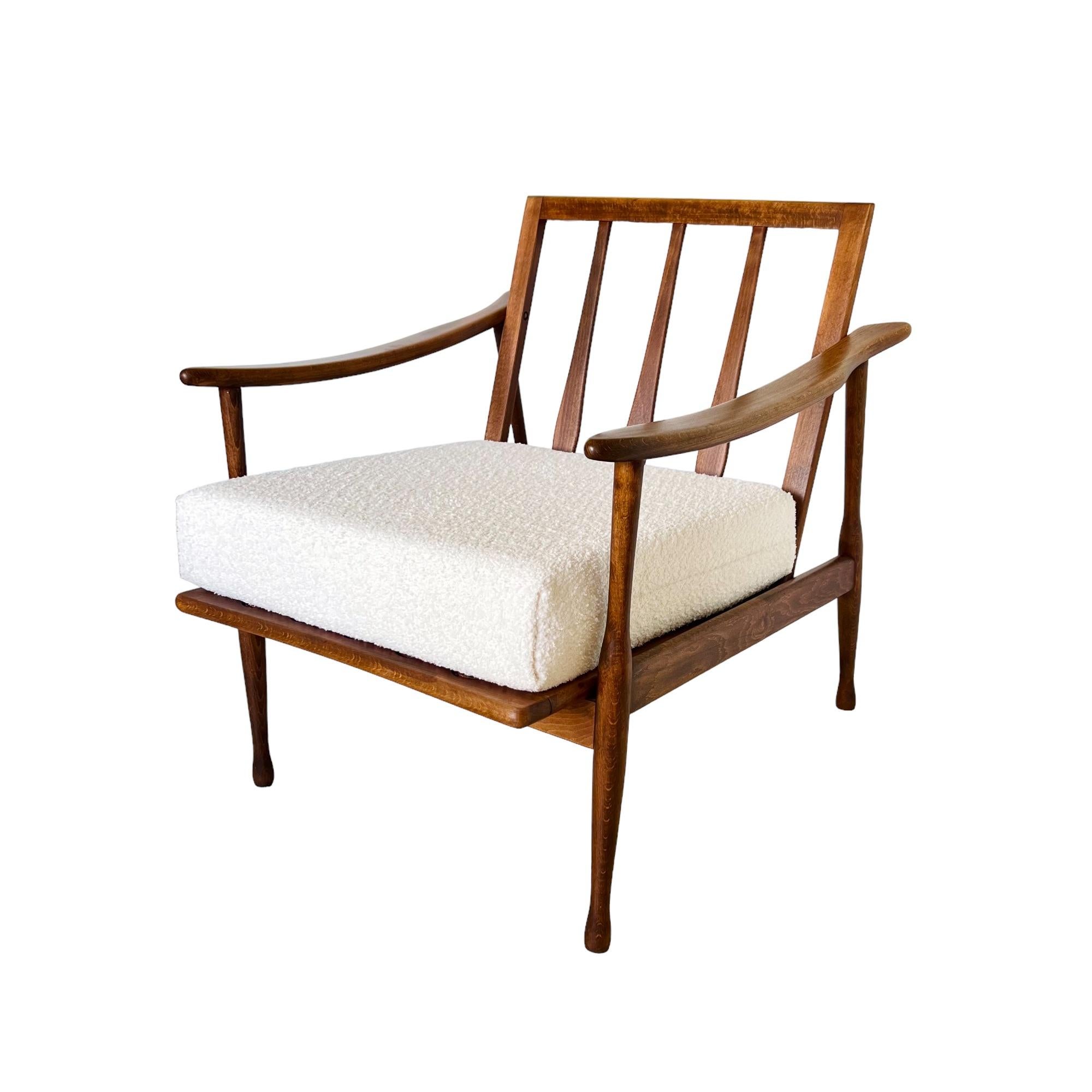 A mid-century modern low lounge chair crafted of beautifully grained walnut with an alabaster white boucle fabric seat cushion. The frame is sculpted in a manner reminiscent of Gio Ponti and Otto Gerdau and may indicate Italian origin, circa. 1950s