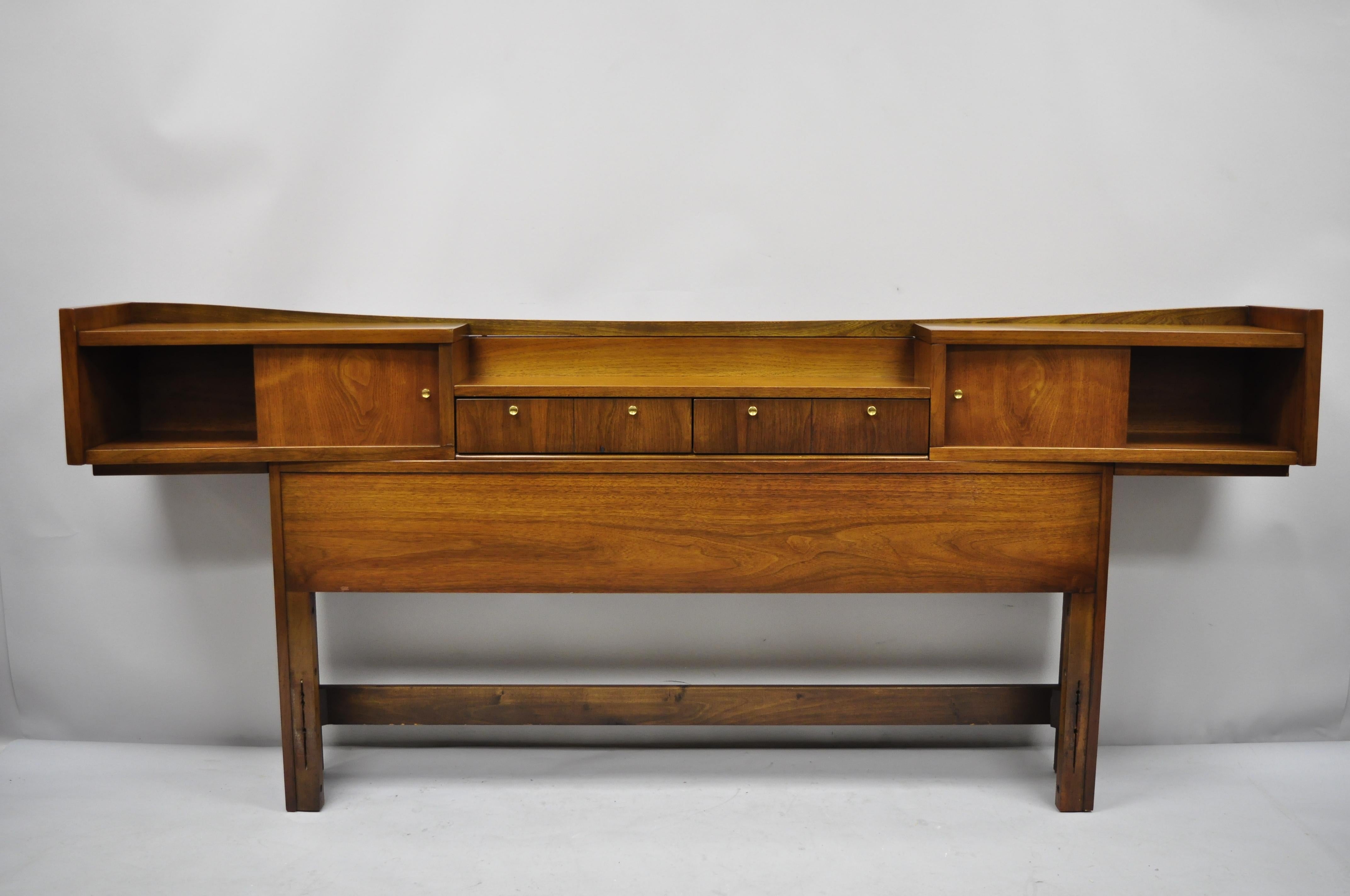 Vintage Mid-Century Modern walnut full size storage bookcase bed headboard. Item features sliding doors, bookcase shelves, floating design, beautiful wood grain, 2 dovetailed drawers, very nice vintage item, sleek sculptural form, circa mid-20th