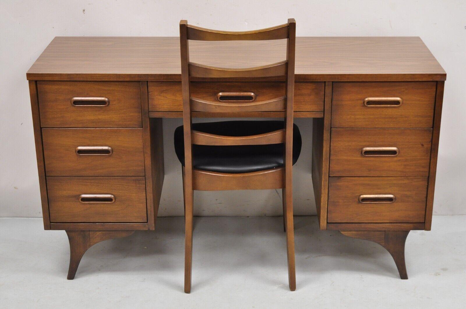 Vintage Mid Century Modern Walnut Sculpted Legs Kneehole Desk & Chair - 2 Pc Set. Ce meuble présente un plateau stratifié marron, 6 tiroirs à queue d'aronde, des poignées de tiroirs et des pieds en bois sculpté, une chaise à dossier en échelle, des