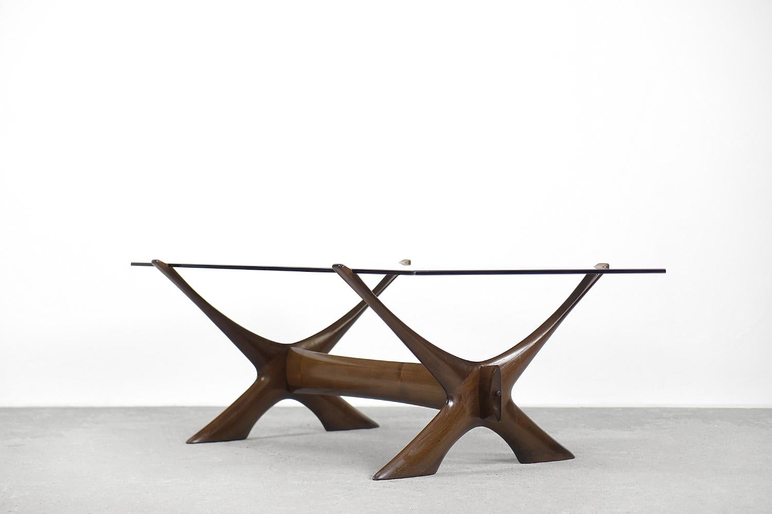 This organically sculptured Condor coffee table was designed by Fredrik Schriever-Abeln and manufactured by Örebro Glass in Sweden during the 1960s. The X-shape base was handcrafted from solid walnut. The distinct frame is contrasted by a linear