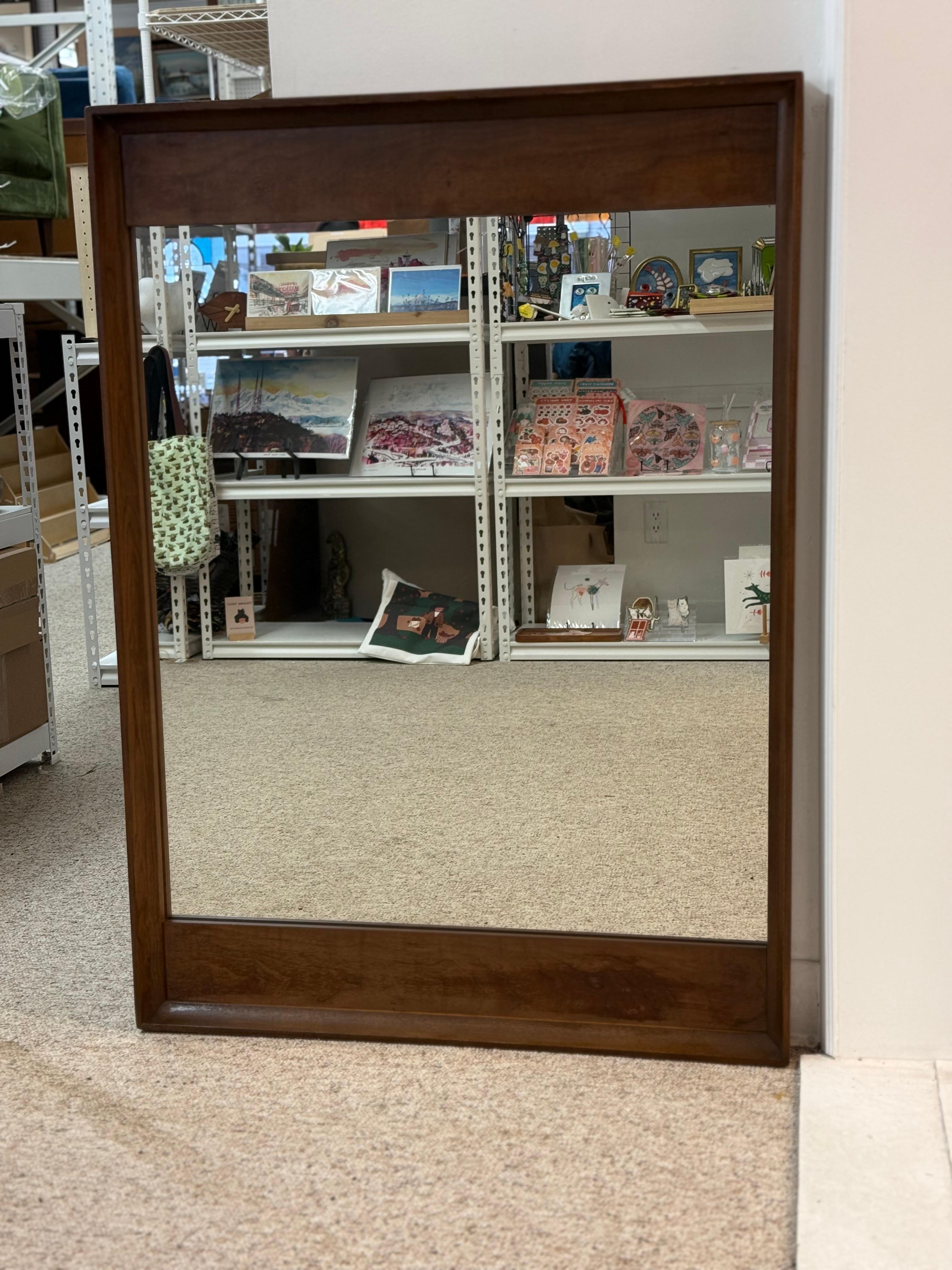 Ce miroir moderne du milieu du siècle de Stanley illustre le mélange de simplicité, de fonctionnalité et de beauté naturelle propre à cette époque. Il présente un design rectangulaire avec un cadre en bois substantiel aux lignes épurées, dans une