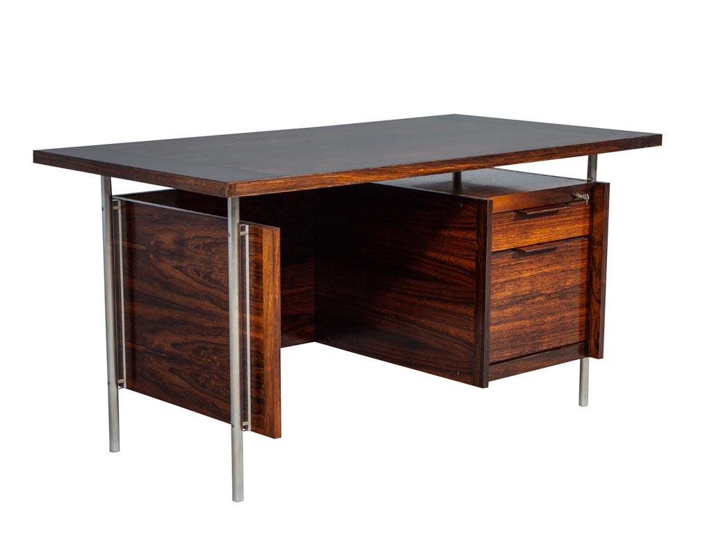Beautifully figured wood grains, this desk has a steel tubular frame, surrounded and accentuated with an acrylic detail. This desk is in its original finish with the original West German Burg + Wachter lock and key. The epitome of midcentury design.