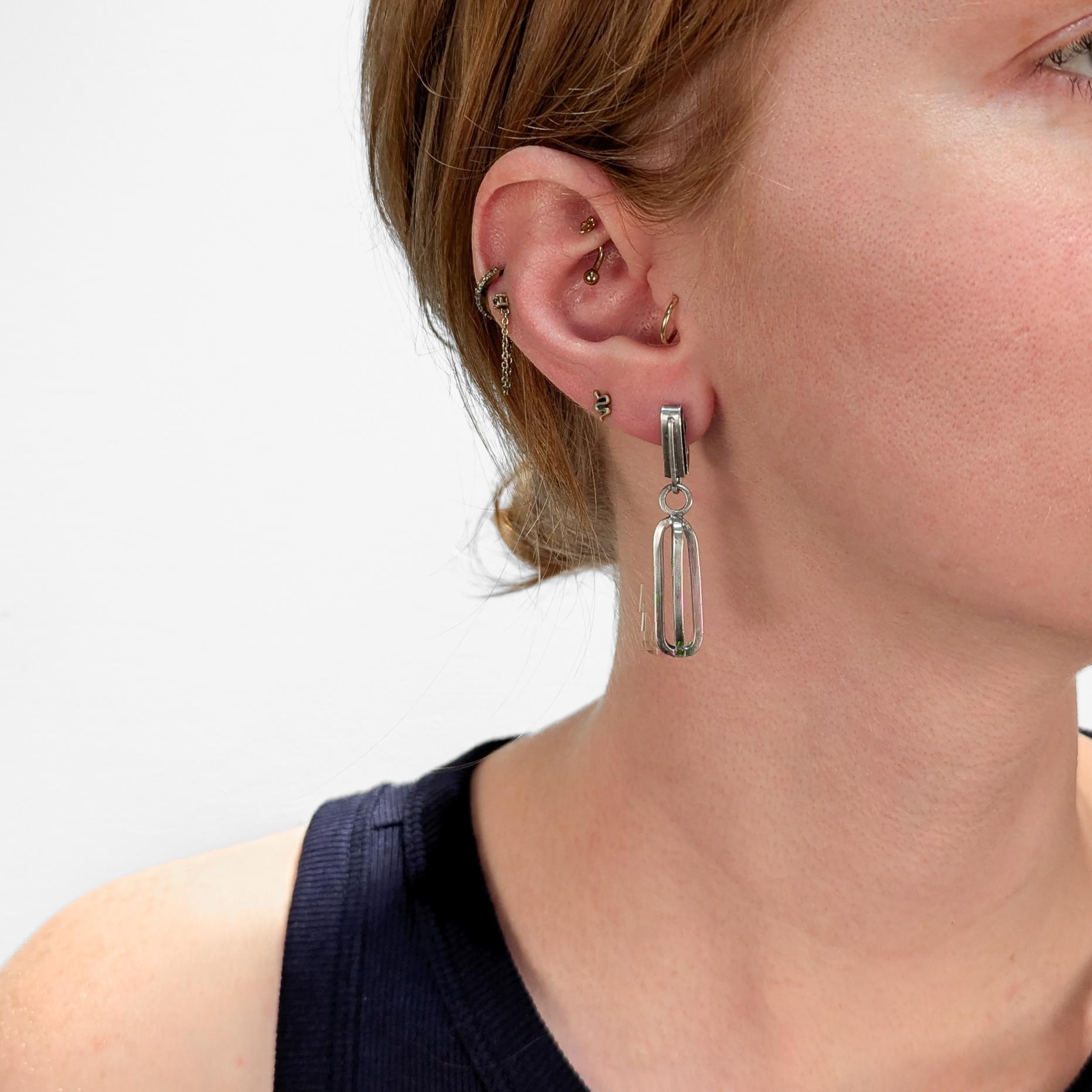 A pair of fine Mid-Century Modern silver drop or dangle earrings.

In sterling silver.

By Paul Lobel. 

Each with an openwork drop supported by a screw back closure.

Lobel was a Romanian-born and New York based jeweler, designer, illustrator who