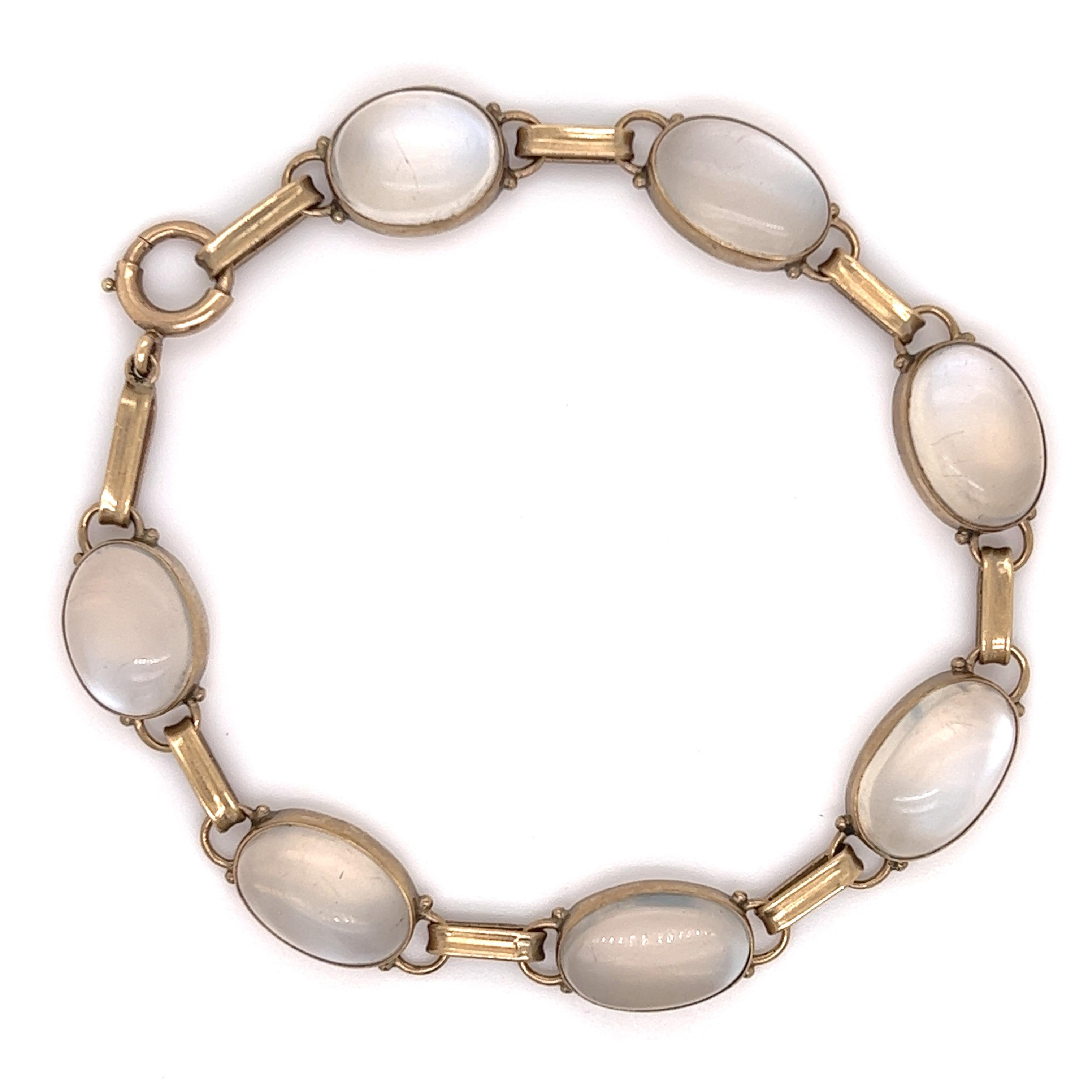Gorgeous design seen on this mid century masterpiece. Simple yet elegant this bracelet is set with seven softly shimmering oval moonstones with faint bluish overtones that glow from within rosy-yellow gold bezels in this straightforward link