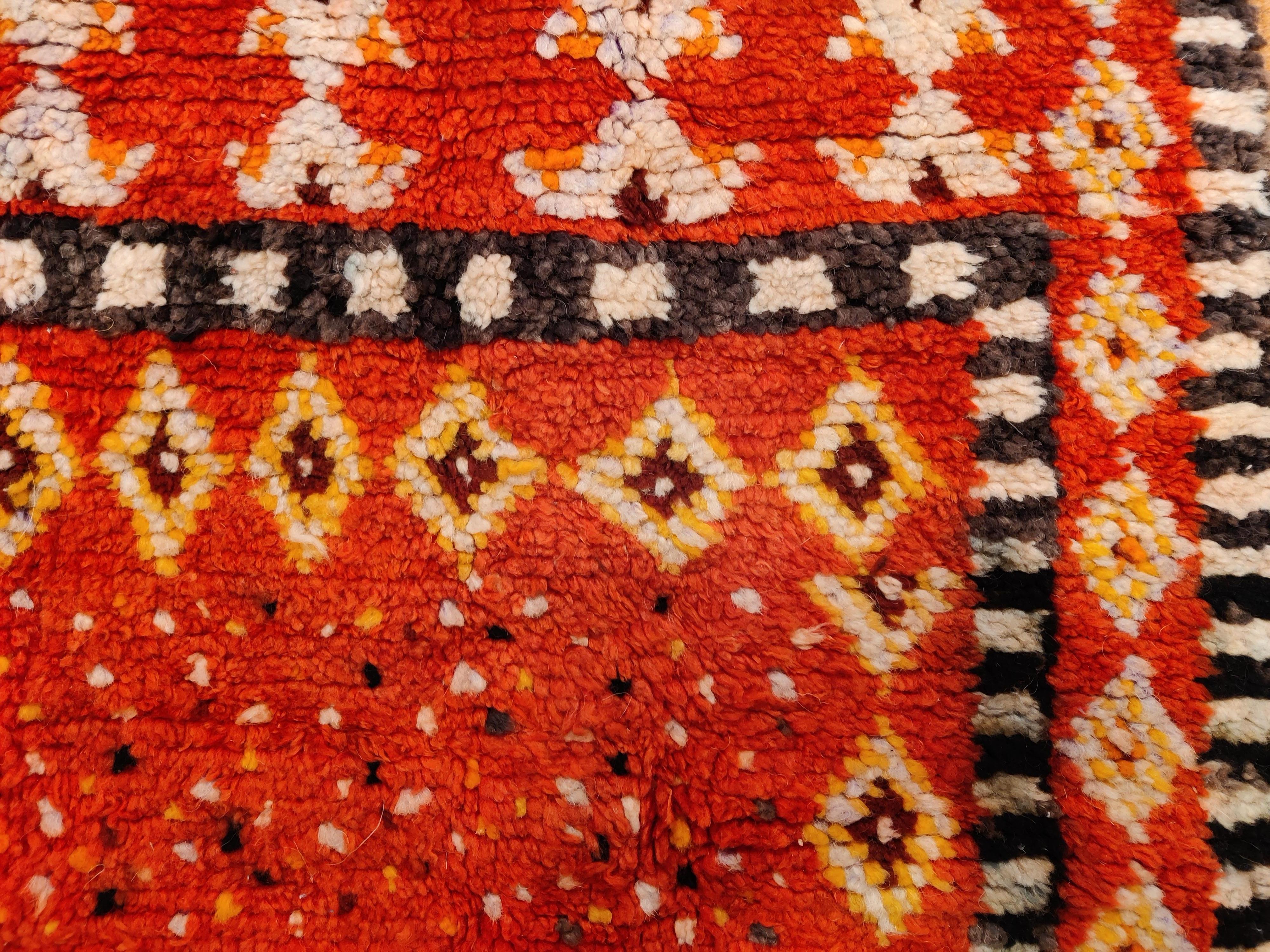 A very finely woven saddle rug from the Ait Ouaouzguite Berber tribe, located in the Jebel Siroua area in southern Morocco, distinguished by an abstract chequerboard and pointillist-type pattern on a rich red background. These rare items were woven