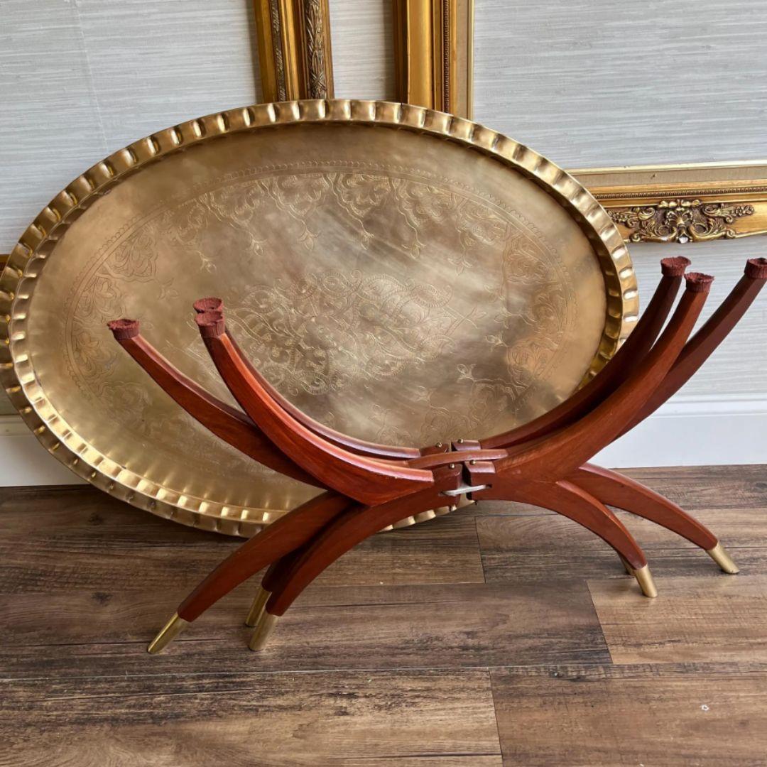 Step into the elegance of mid-century modern design with this exquisite oval brass coffee table, a true reflection of the era's style and craftsmanship. Featuring a spider-leg base that effortlessly folds for versatility, this piece combines form