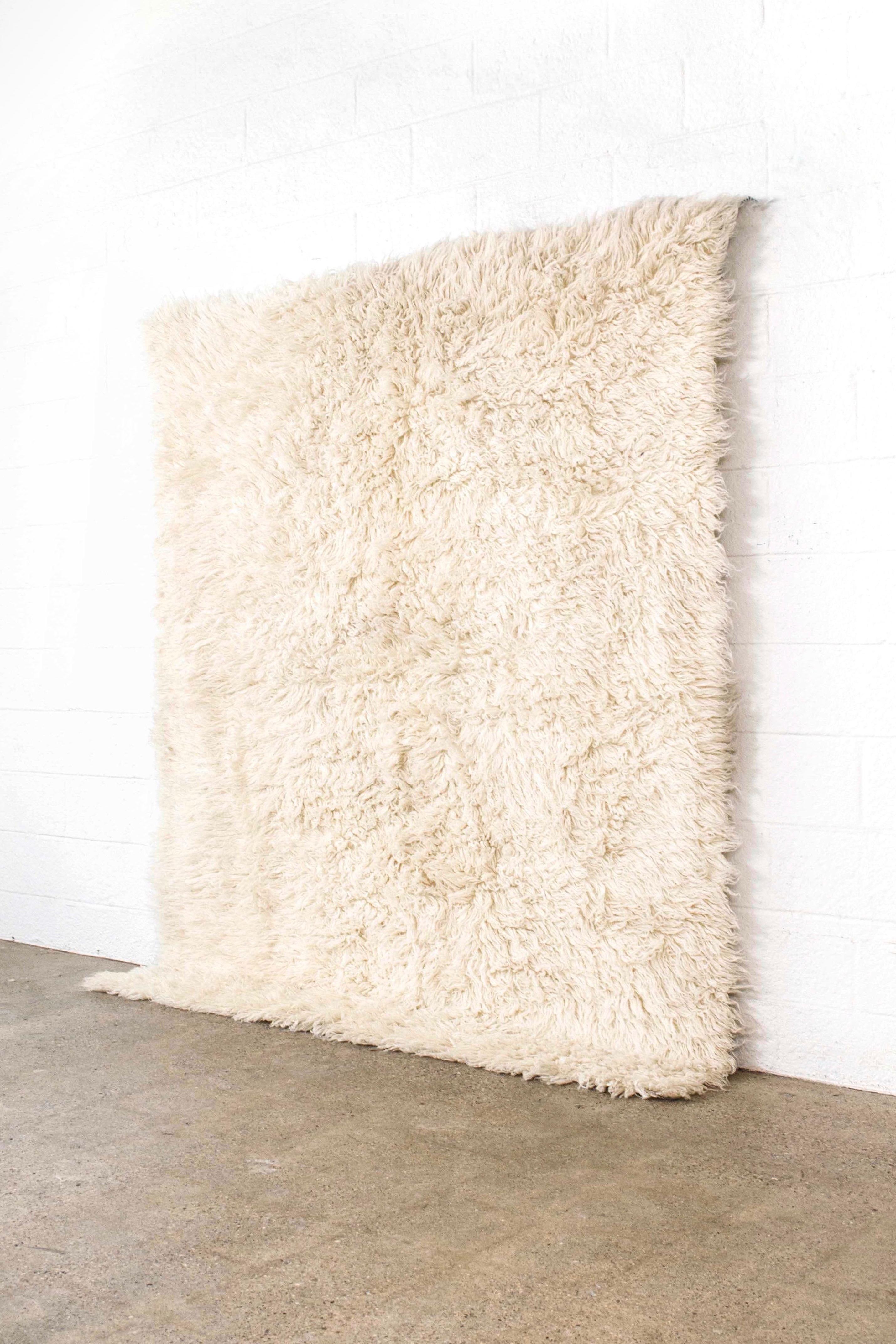 This beautiful large vintage wool shag rug circa 1970 is handwoven from 100% un-dyed wool and has a soft and luxurious thick shaggy pile. The clean, Minimalist design of this natural ivory carpet makes it the perfect complement for any contemporary