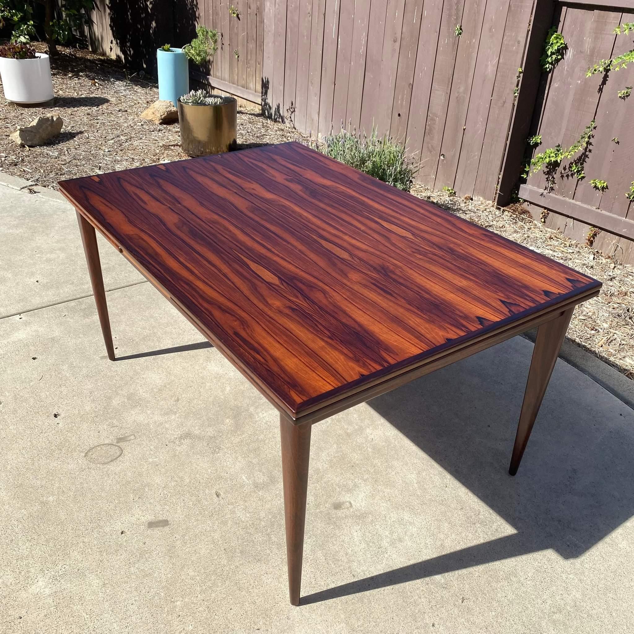 Pictures do not do justice on this beauty! Now available is an amazing rosewood dining table by Niels Møller for J.L. Møllers Møbelfabrik c1960s. Features a gorgeous bookmatched grain that been professionally refinished. Measures approximately 59L x
