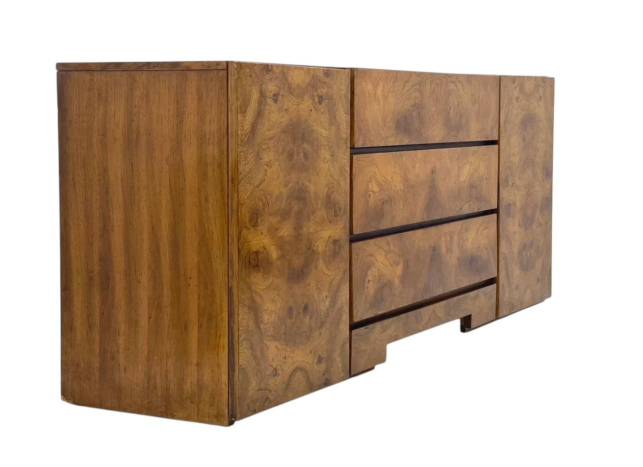 Il comò è un pezzo moderno di metà secolo caratterizzato da un design elegante e a basso profilo con una ricca e calda finitura in legno. Ha una combinazione di tre cassetti con tiretti orizzontali e ante su entrambi i lati, che rivelano un
