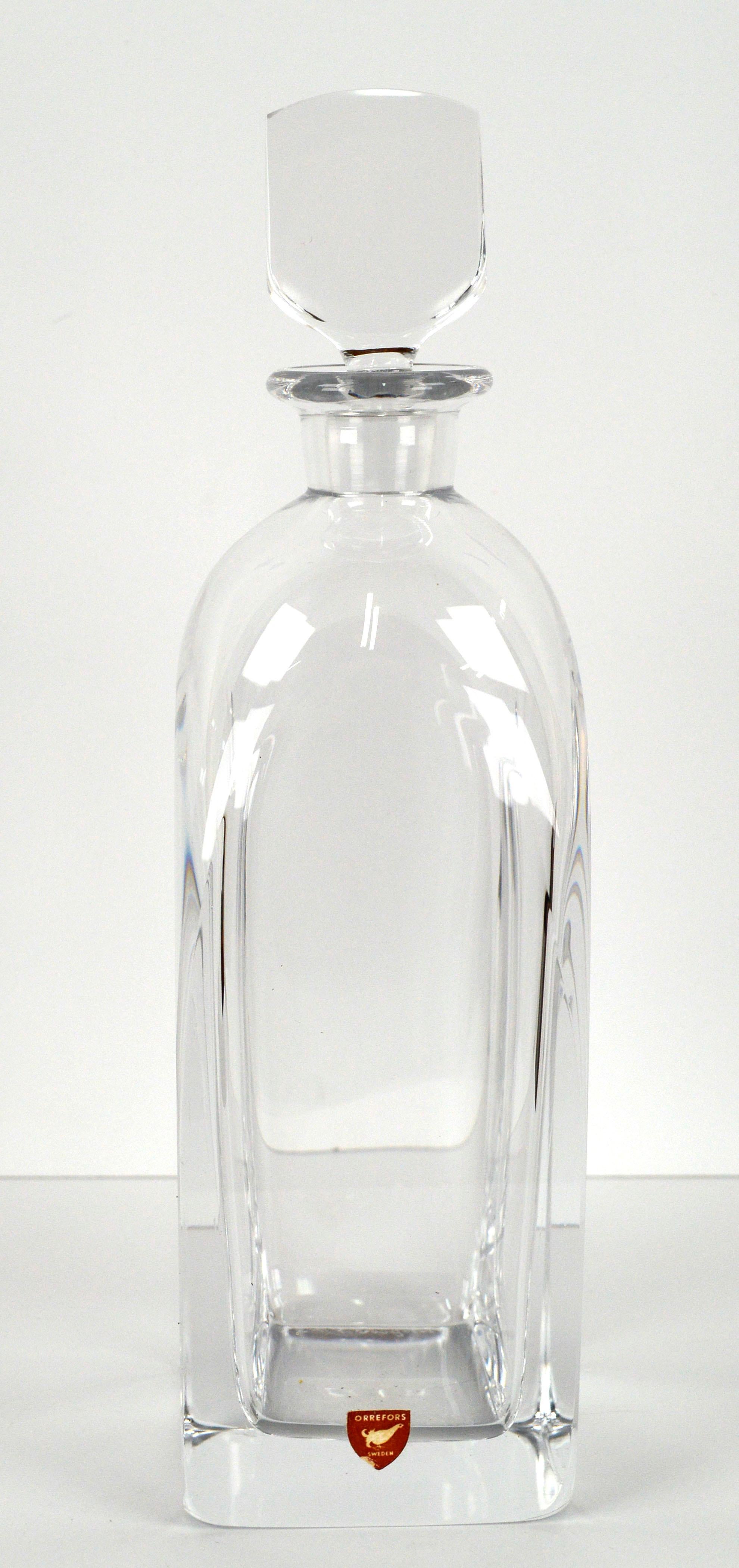 Elegant Mid-Century Modern vintage crystal decanter with stopper by Orrefors (Swedish, founded 1898), c. 1960's. Engraved signature to base Orrefors HM 2498 - this particular style was by Edvard Hall. 

Includes original red Orrefors Sweden