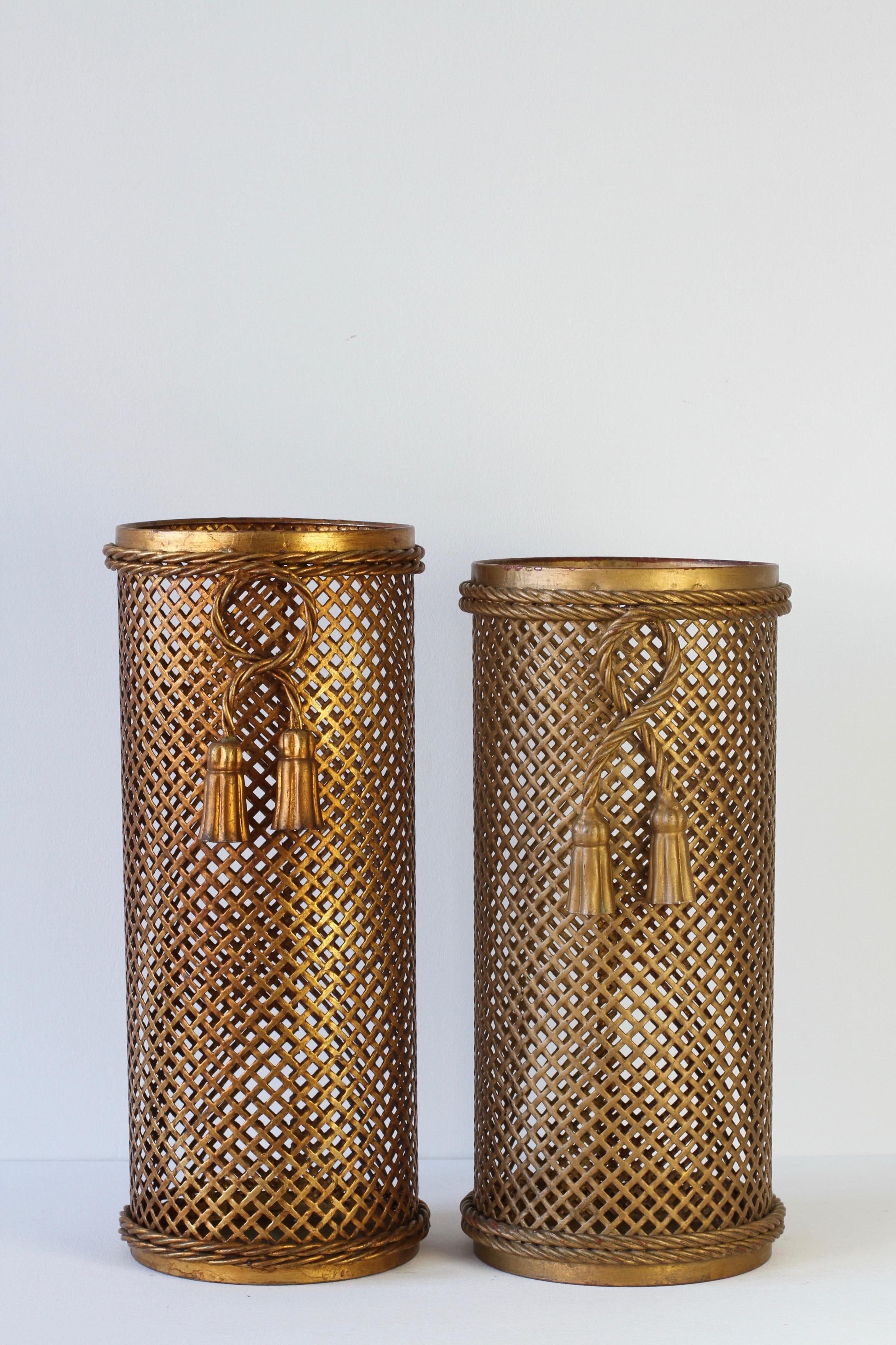Stunning pair of midcentury gold / gilt / gilded Hollywood Regency style umbrella Stands / holders made in Florence, Italy, circa 1950 attributed to Li Puma Firenze. The perforated lattice patterned metalwork with bent rope and tassel details