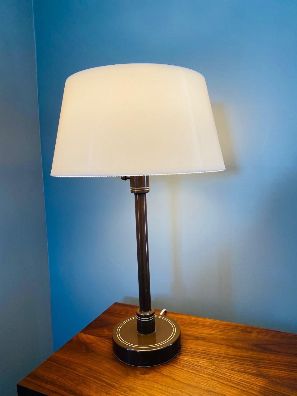 This piece was created in the 1960s. This was at the time a forward thinking futuristic design as the world looked beyond the atomic age and into space. Clean, minimal and current into today. This lamp presents a plastic shade and an enameled brown