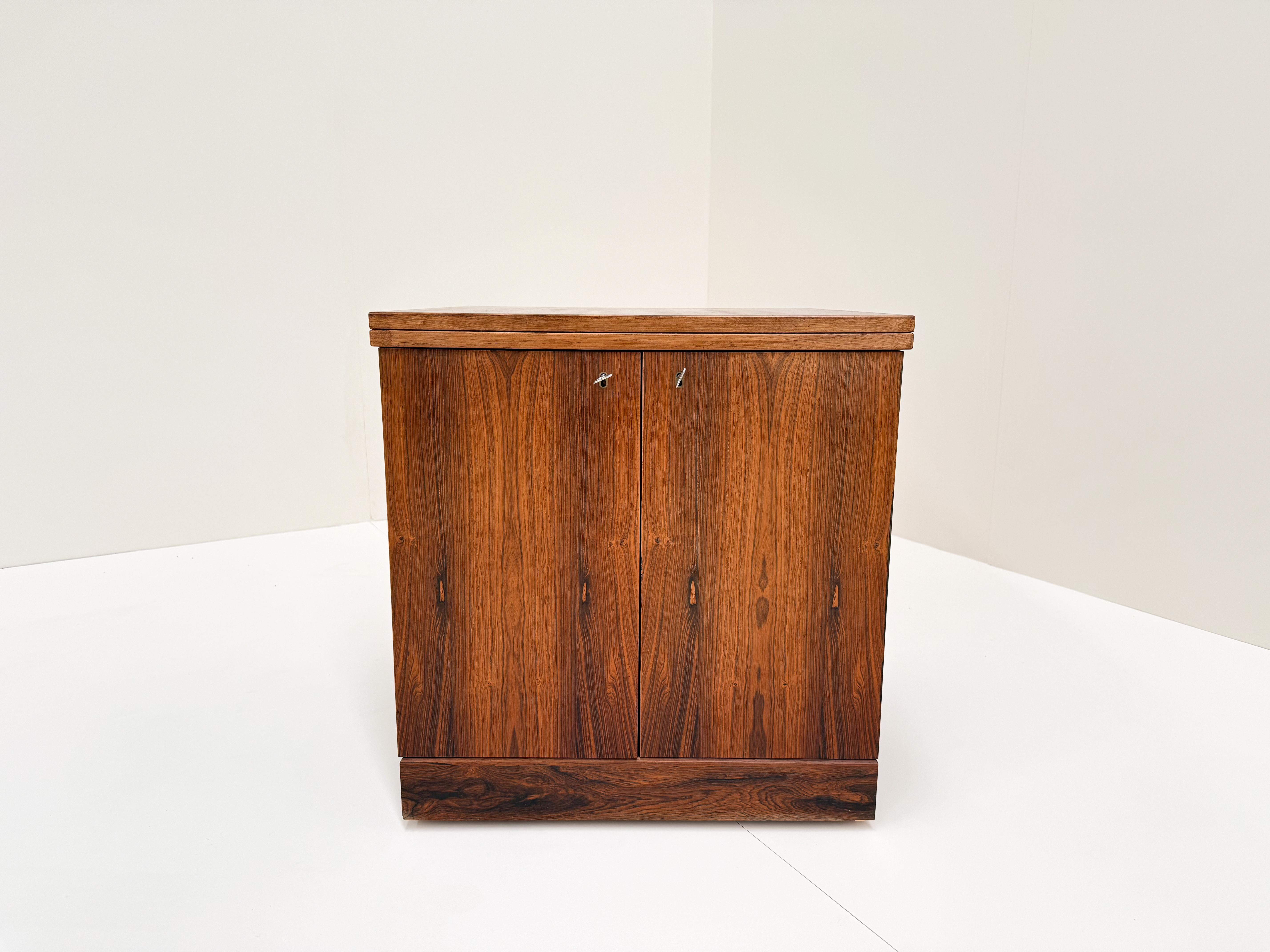 A sleek and elegant cube bar cabinet designed by Torbjørn Afdal for Bruksbo, Norway, in the early 1960s. Crafted from rich rosewood, this stylish piece features a clever expandable design, opening on both sides with double doors. Inside, it offers