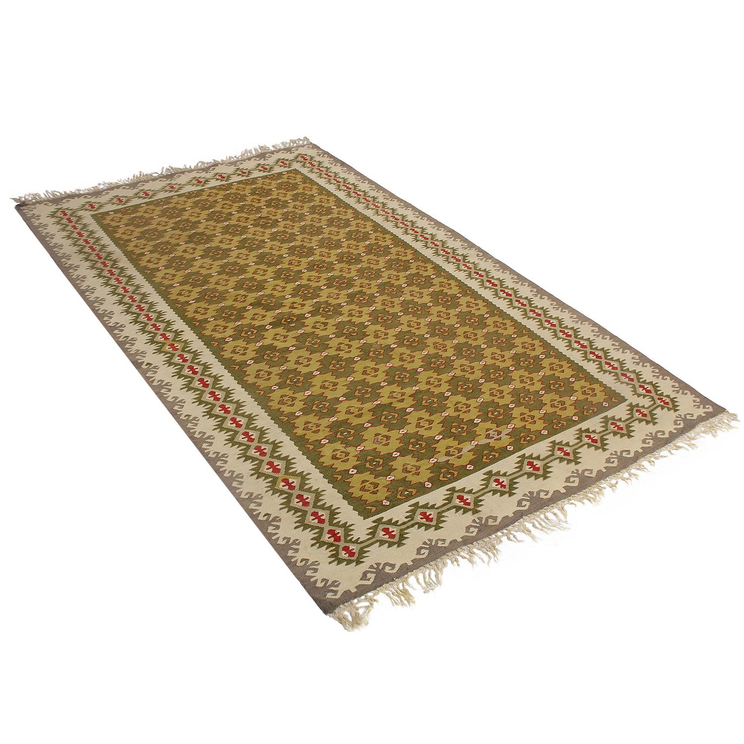 Handwoven in Turkey originating between 1950-1960, this vintage midcentury wool Kilim hails from the seaside town of Sarkoy (Sarköy). The repetition of the geometric field pattern plays well off the alternating hues of forest and olive green, given