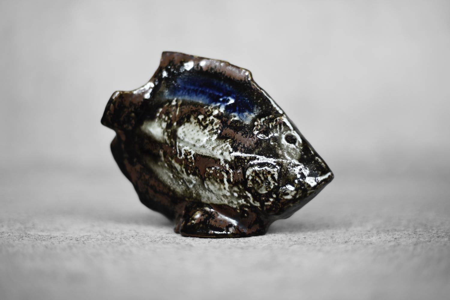 This stoneware Fish sculpture was designed by Carl-Harry Stålhane for the Swedish porcelain factory Rörstrand during the 1960s. Made of high-quality materials in shades of brown and cobalt. Hand-painted and glazed. The figurine is inspired by