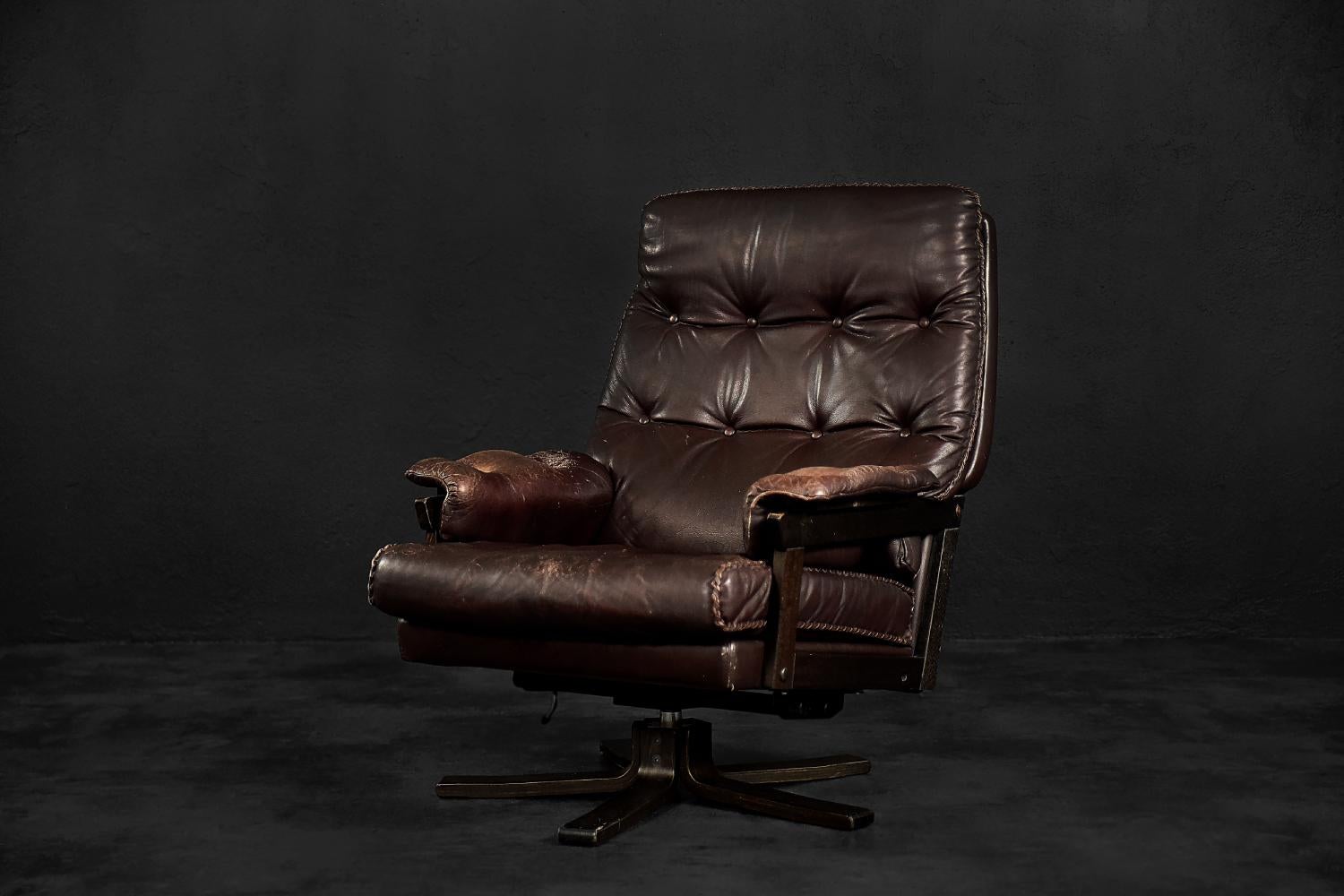 This modernist armchair was made in Denmark during the 1970s. The frame of the armchair is made of wood. It is upholstered in high-quality, soft, dark brown natural leather. The base is a rotating leg. The wide seat and the high backrest of the