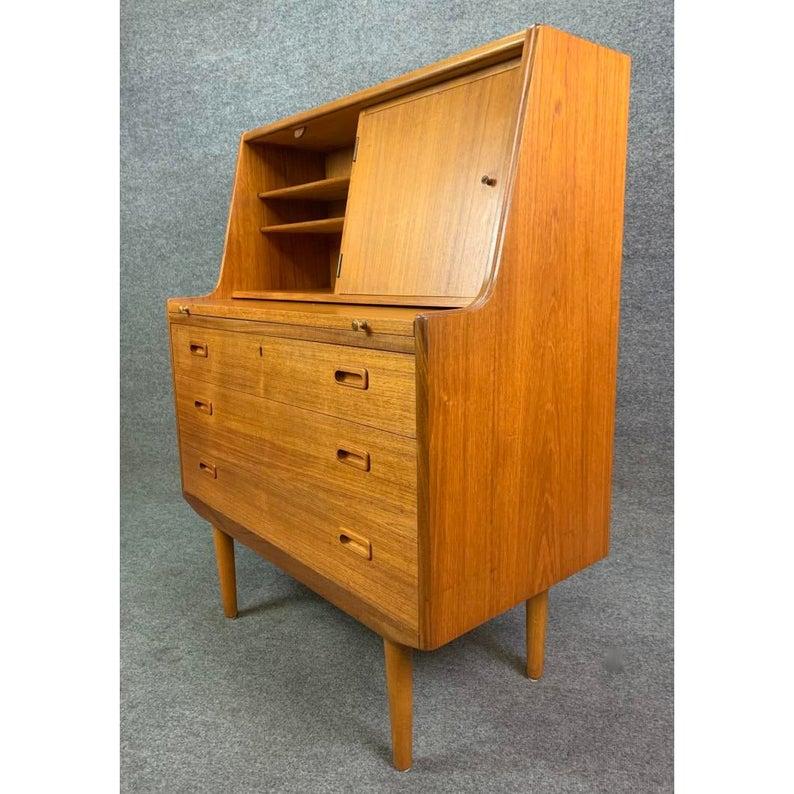 Here is an elegant secretary with a pullout / pull-out desk in teak wood recently imported from Sweden to California.
This lovely pieces a very nice vibrant wood grain and features on its upper side two cubbies with shelving (one hiding behind a