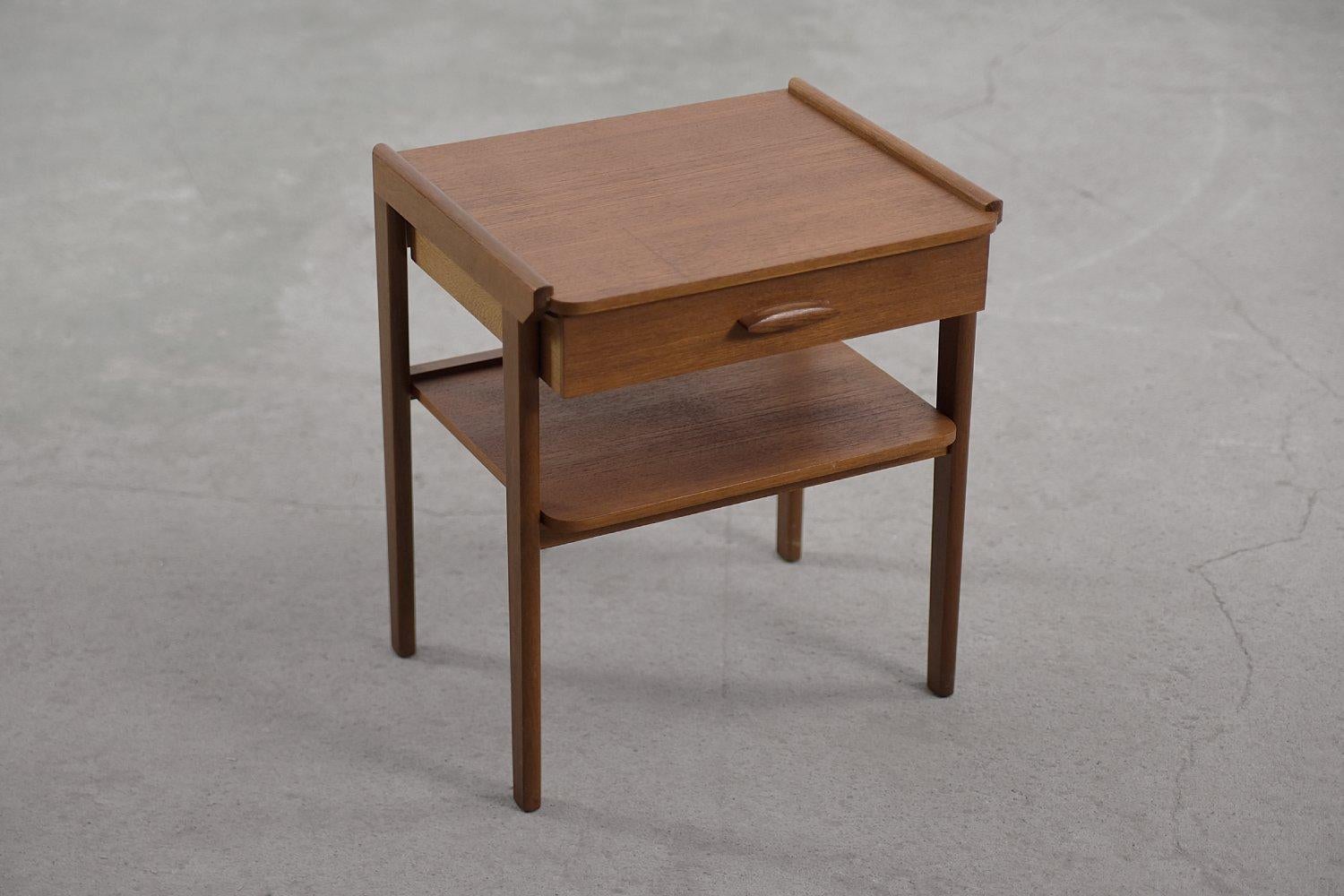 This modernist night table was manufactured in Sweden during the 1950s. It is finished with teak wood in honey brown color. This kind of wood has a high content of natural oily substances, which makes it highly water-resistant. The cabinet has one
